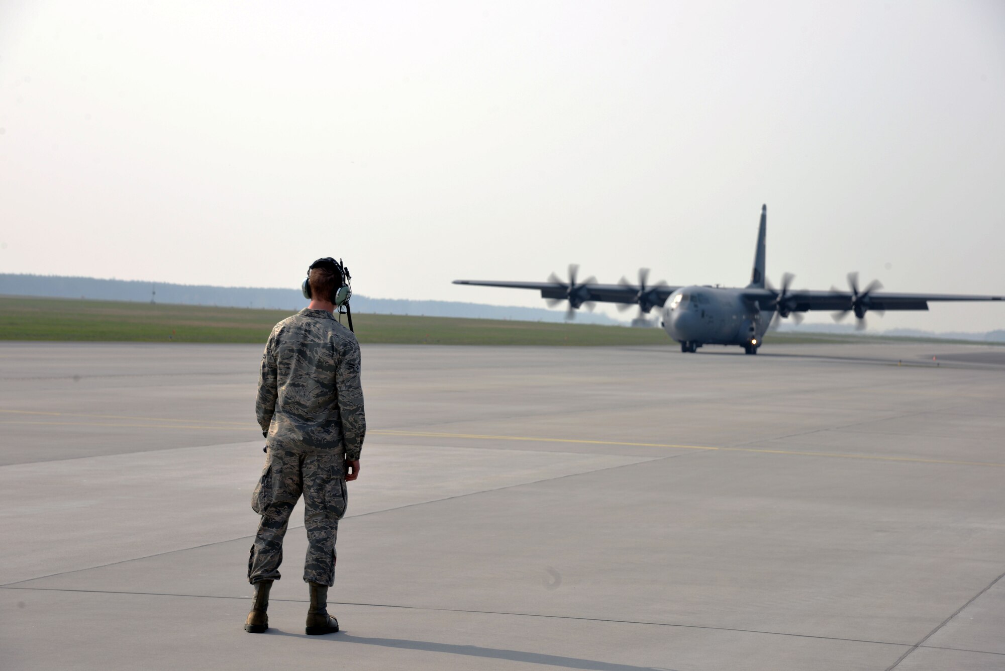 An Airman from the 86th Airlift Wing, Ramstein Air Base, Germany, directs a U.S. C-130J Super Hercules aircraft taxiing in from flying a training mission with the Polish armed forces at Powidz Air Base, Poland, April 3, 2014. Three C-130J and more than 100 U.S. personnel will train to strengthen partnership capacity for real-world NATO opersations until April 12 at the U.S. Aviation Detachment. There are two more scheduled Av-Det rotations this fiscal year. (U.S. Air Force photo by 2nd Lt. Katrina Cheesman/Released)