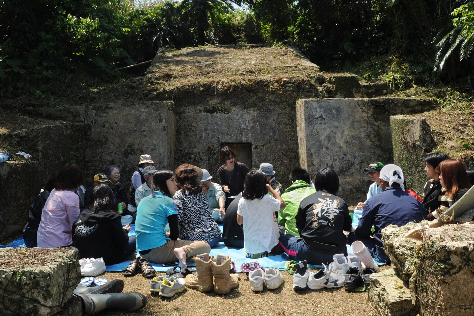 Local citizens gather around their family tomb after praying in observance of Shimi in the Munitions Storage Area on Kadena Air Base, Japan, April 6, 2014. During Shimi, one of the only times locals can visit tombs located in the restricted area, Okinawans clear overgrown plants from the area surrounding their tomb before gathering extended family members to pray, eat and enjoy each other’s company.  About 100 Airmen volunteered to escort more than 400 visiting locals this year.  (U.S. Air Force photo by Airman 1st Class Zade C. Vadnais)