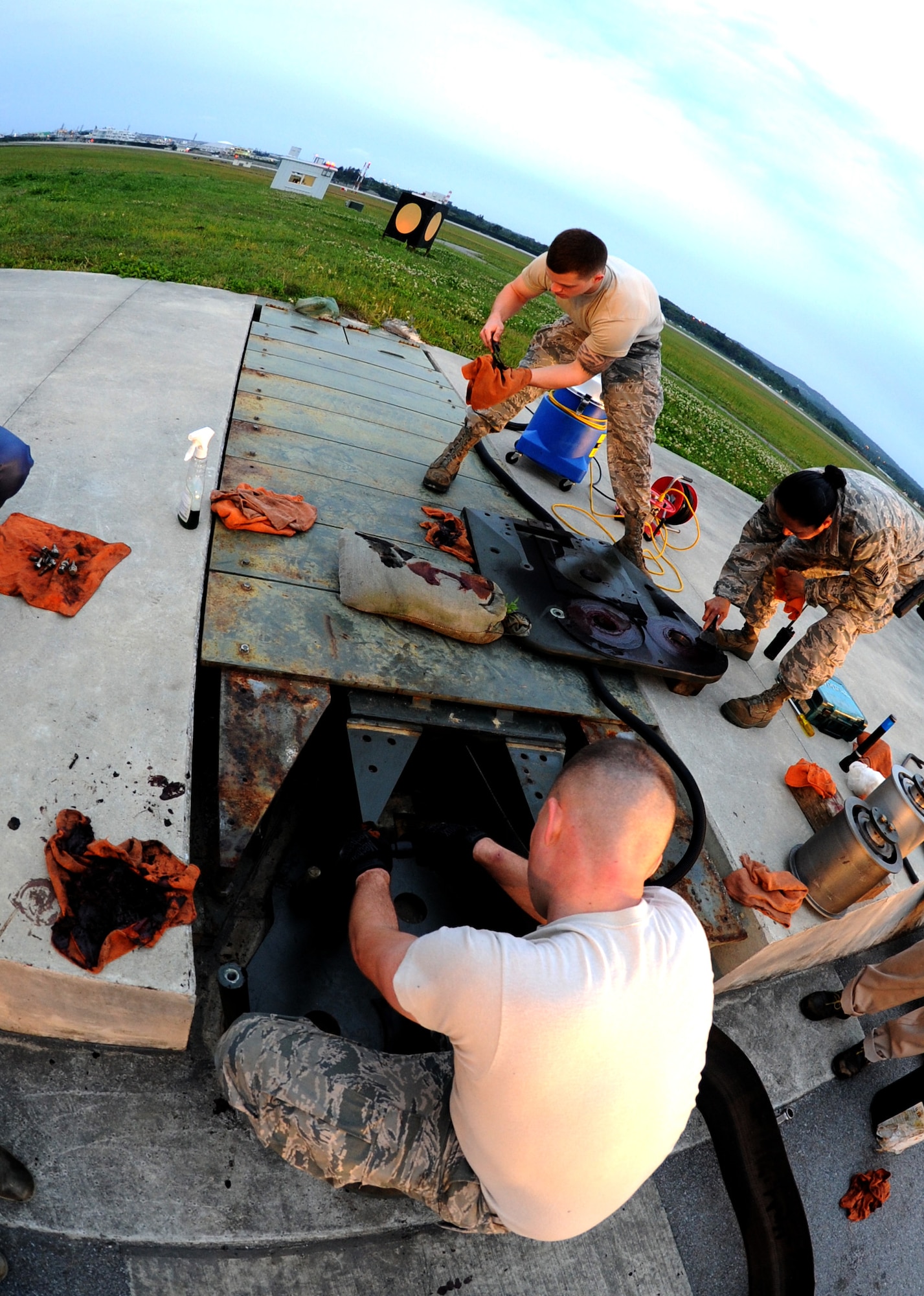 Members from the 18th Civil Engineer Squadron work to remove and clean sheave rollers prior to reinstalling a BAK-12 Aircraft Arresting System on the flightline of Kadena Air Base, Japan, April 7, 2014. Performed every 36 months, the maintenance is done to ensure smooth exit of the nylon tapes and avoid damages when aircraft come in to land during in-flight emergencies. (U.S. Air Force photo by Airman 1st Class Keith James)