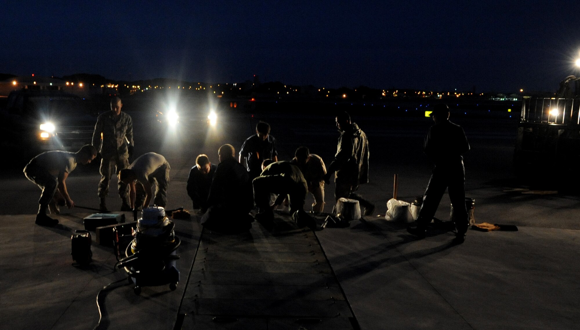 Members from the 18th Civil Engineer Squadron work to remove and clean sheave rollers prior to reinstalling a BAK-12 Aircraft Arresting System on the flightline of Kadena Air Base, Japan, April 7, 2014. Performed every 36 months, the maintenance is done to ensure smooth exit of the nylon tapes and avoid damages when aircraft come in to land during in-flight emergencies. (U.S. Air Force photo by Airman 1st Class Keith James)