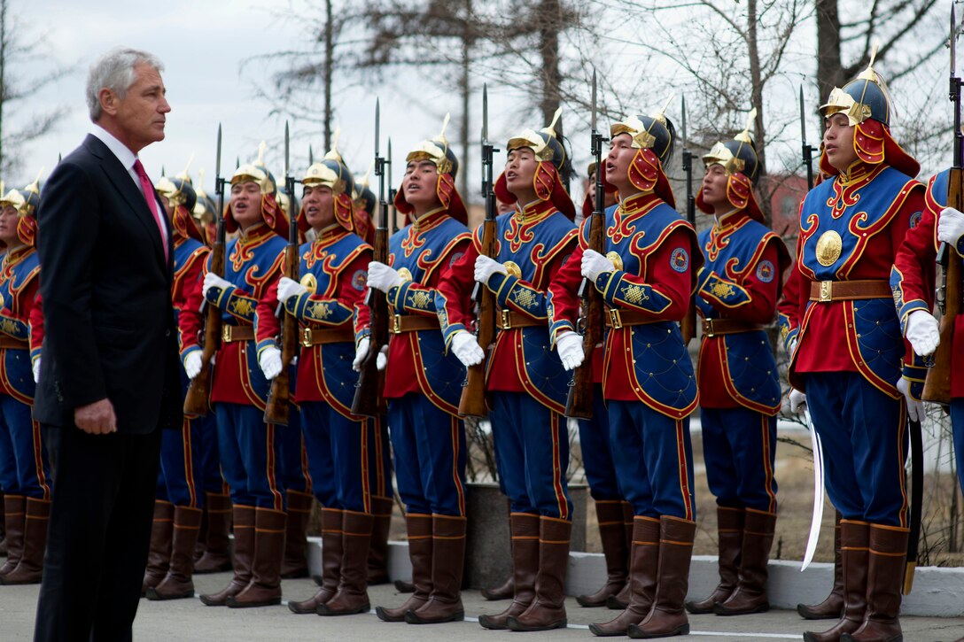 U.S. Defense Secretary Chuck Hagel stands as Mongolian soldiers present arms and yell during an honor cordon at the Mongolian Ministry of Defense in Ulaanbaatar, Mongolia, April 10, 2014.