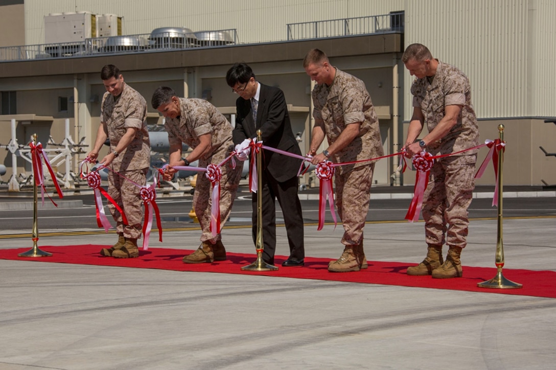 From left to right, Col. Robert V. Boucher, commanding officer of Marine Corps Air Station Iwakuni, Japan, Maj. Gen. Juan G. Ayala, commander of Marine Corps Installations Command, Takafumi Fujii, director general of the Chugoku-Shikoku Defense Bureau, Brig. Gen. Steven Rudder, commanding general of 1st Marine Aircraft Wing, and Col. Hunter Hobson, commanding officer of Marine Aircraft Group 12, cut a ceremonial ribbon signifying the official opening of new facilities during the MAG-12 and Marine Aviation Logistics Squadron 12 ribbon cutting ceremony aboard station March 27, 2014. The Defense Policy Review Initiative built the new facilities as part of the ongoing construction focused on rebuilding 77 percent of the station.