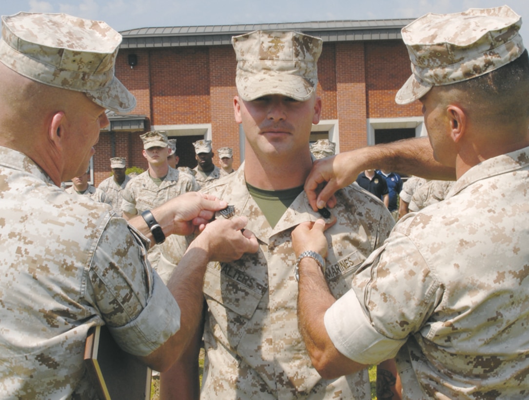 Meritoriously promoted Gunnery Sgt. Daniel G. Walters (center) company gunnery sergeant and postal chief, Marine Corps Logistics Base Albany, pins on his new rank in front of his family, Marines and civilian-Marines, April 2, at Schmid Field, here. Maj. Brent Richardson (right) commanding officer, Aviation Squadron-1, Marine Aviation Training Support Group-21, Pensacola, Fla., and Sgt. Maj. Conrad Potts, sergeant major, MCLB Albany, placed on the new chevrons.