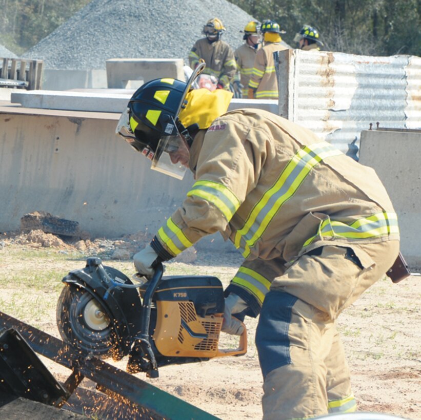 A fireman cuts debris to be repurposed as a tool to assist in the rescue of a simulated victim April 1 during Twisting Thunder 2014 at Marine Corps Logistics Base Albany.