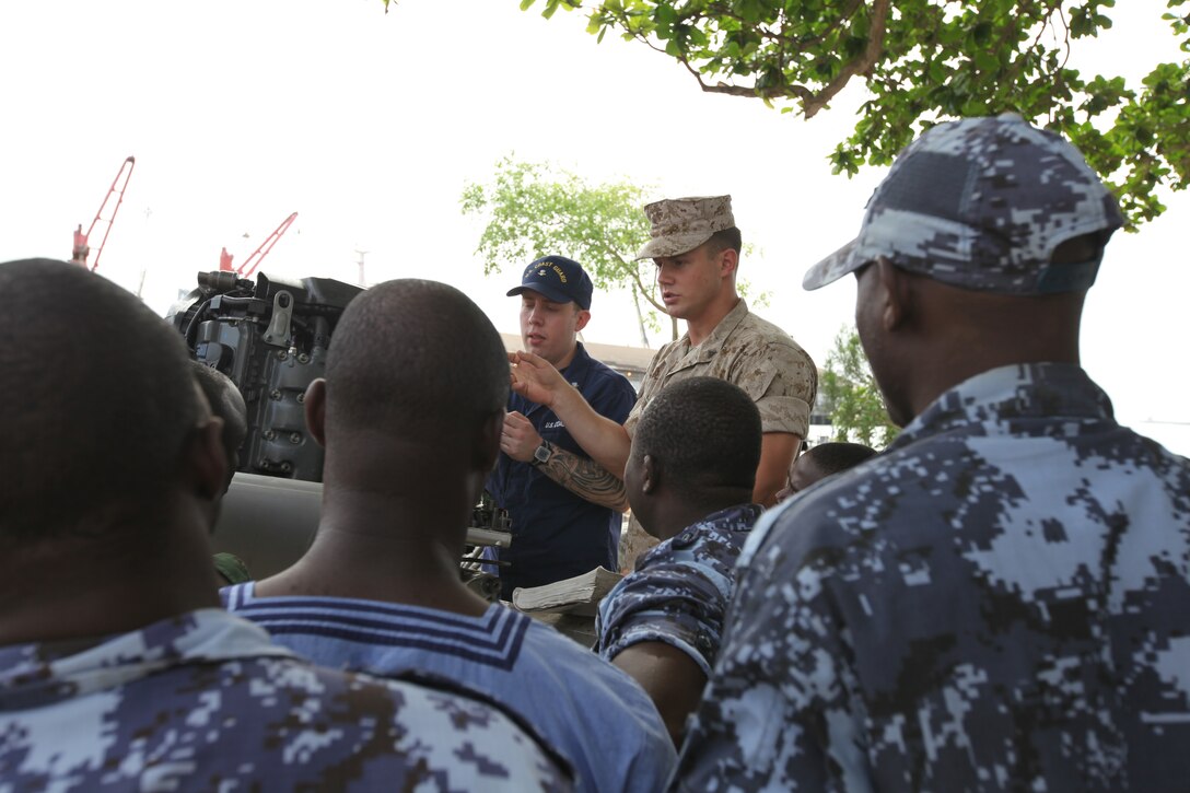 A group of sailors with the Togolese Navy watch as Lance Cpl. Tyler Jackson, a Marine with Special-Purpose Marine Air-Ground Task Force Africa 14.1, and Petty Officer 3rd Class Brian Spence, a Coastguardsman with U.S. Coast Guard Station Seattle, discuss small-boat engine mechanics in Lomé, Togo, March 25. Jackson and Spence put together a week-long training program of classroom instruction and practical application so the two groups of service members could partner together to fix engines. Established in 2011, Special-Purpose Marine Air-Ground Task Force Africa 14.1 is charged with supporting U.S. Africa Command and Marine Corps Forces Europe and Africa’s theater security cooperation requirements.