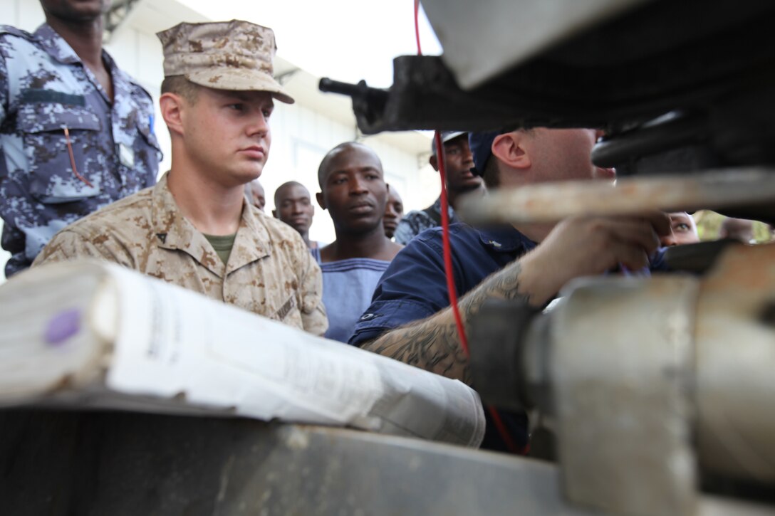 Lance Cpl. Tyler Jackson, a Marine with Special-Purpose Marine Air-Ground Task Force Africa 14.1, looks on as Petty Officer 3rd Class Brian Spence, a Coastguardsman with U.S. Coast Guard Station Seattle, explains the electronic control module on a small-boat engine to a group of sailors from the Togolese Navy in Lomé, Togo, March 25. Jackson and Spence put together a week-long training program of classroom instruction and practical application so the two groups of service members could partner together to fix engines. Established in 2011, Special-Purpose Marine Air-Ground Task Force Africa 14.1 is charged with supporting U.S. Africa Command and Marine Corps Forces Europe and Africa’s theater security cooperation requirements.
