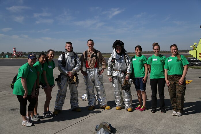 Headquarters and Headquarters Squadron spouses pose for a picture with Aircraft Rescue and Fire Fighting Marines on the flight line aboard Marine Corps Air Station New River, N.C., April 5, as apart of an In Their Boots event. During the event, spouses visited a static display of aircraft aboard the air station and viewed ARFF Marines give a demonstration of the speed they have to have during an emergency. 


