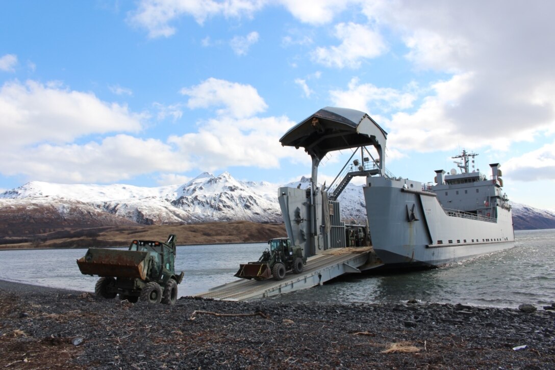 Marines from Marine Wing Support Squadron (MWSS) 471, Marine Aircraft Group 41, 4th Marine Aircraft Wing, Marine Forces Reserve unload a Backhoe Loader followed by a Rubber-Tired, Articulated Steering, Multi-Purpose Tractor in Old Harbor, Alaska, April 7, 2014. The engineer equipment will be used during Innovative Readiness Training Old Harbor, a project to extend a remote runway beginning in May running through August. The project will continue work started by the Marine Corps Reserve in 2013 to extend a remote village runway by about 2000 feet.  