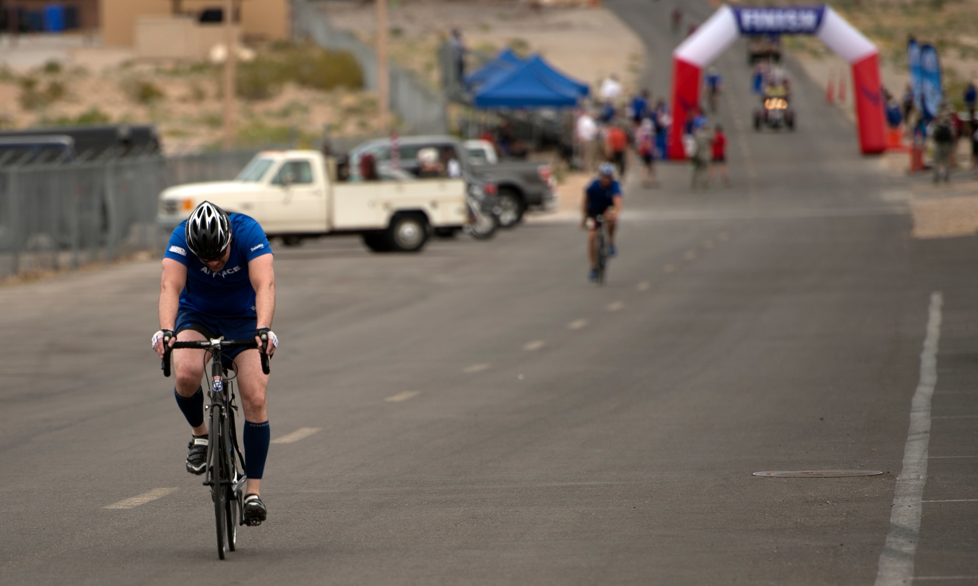 Cyclists pass through the finish line during the 18-mile men’s bicycle open April 9, 2014, at Nellis Air Force Base, Nev.  The cyclists circled a two mile loop based upon how many miles they needed to accomplish for their particular race.  (U.S. Air Force photo/Senior Airman Jette Carr)