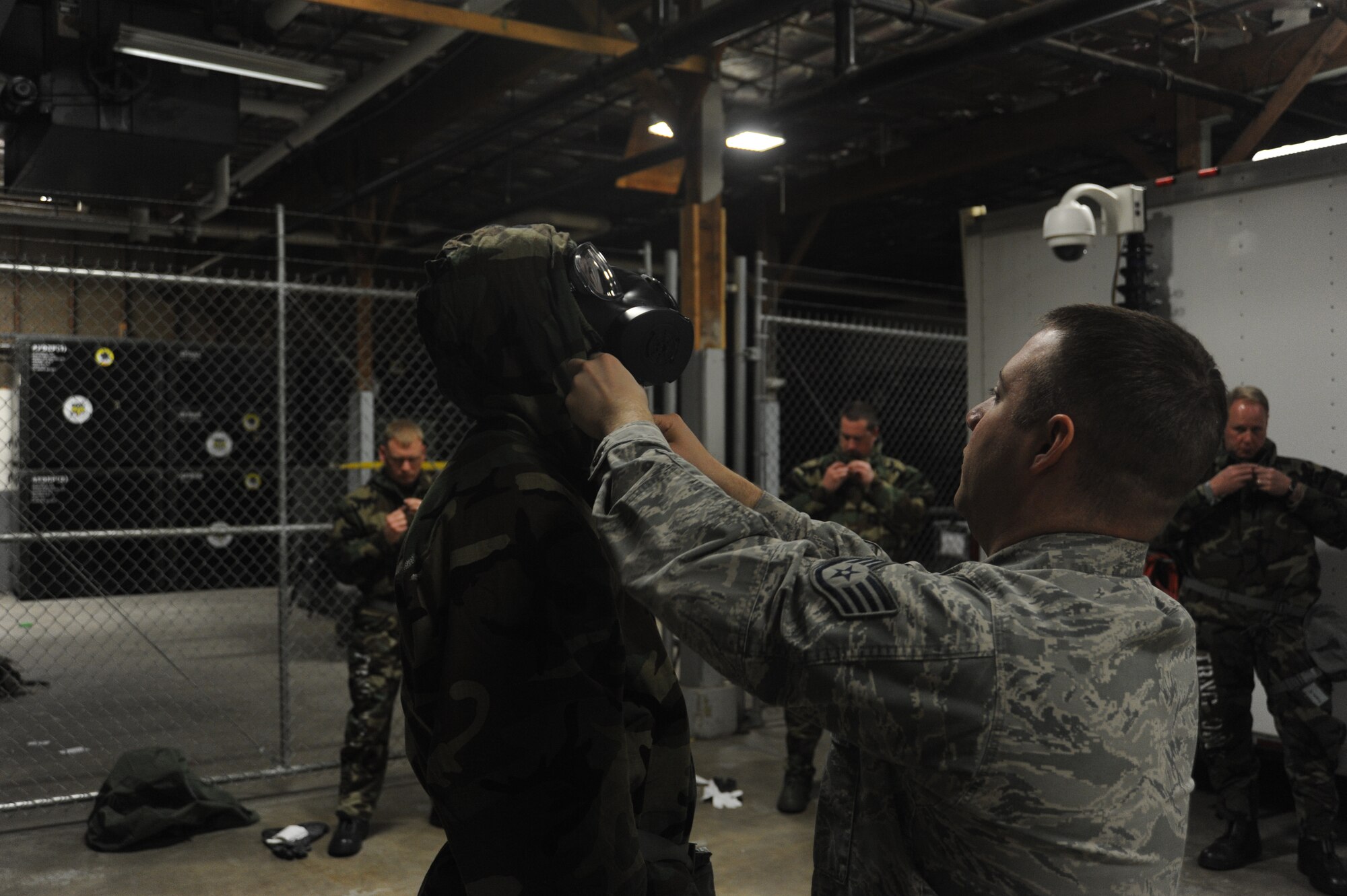 Staff Sgt. Jeremy Parks tightens the straps on an Airman’s mission oriented protective posture gear at Fairchild Air Force Base, Wash., April 10, 2014.  The demonstration was a segment of the weekly Chemical, Biological, Radiological and Nuclear training held at the base.  Parks is the 92nd Chemical Engineer Squadron emergency management logistics NCO in charge.  (U.S. Air Force photo by Airman 1st Class Sam Fogleman/Released)
