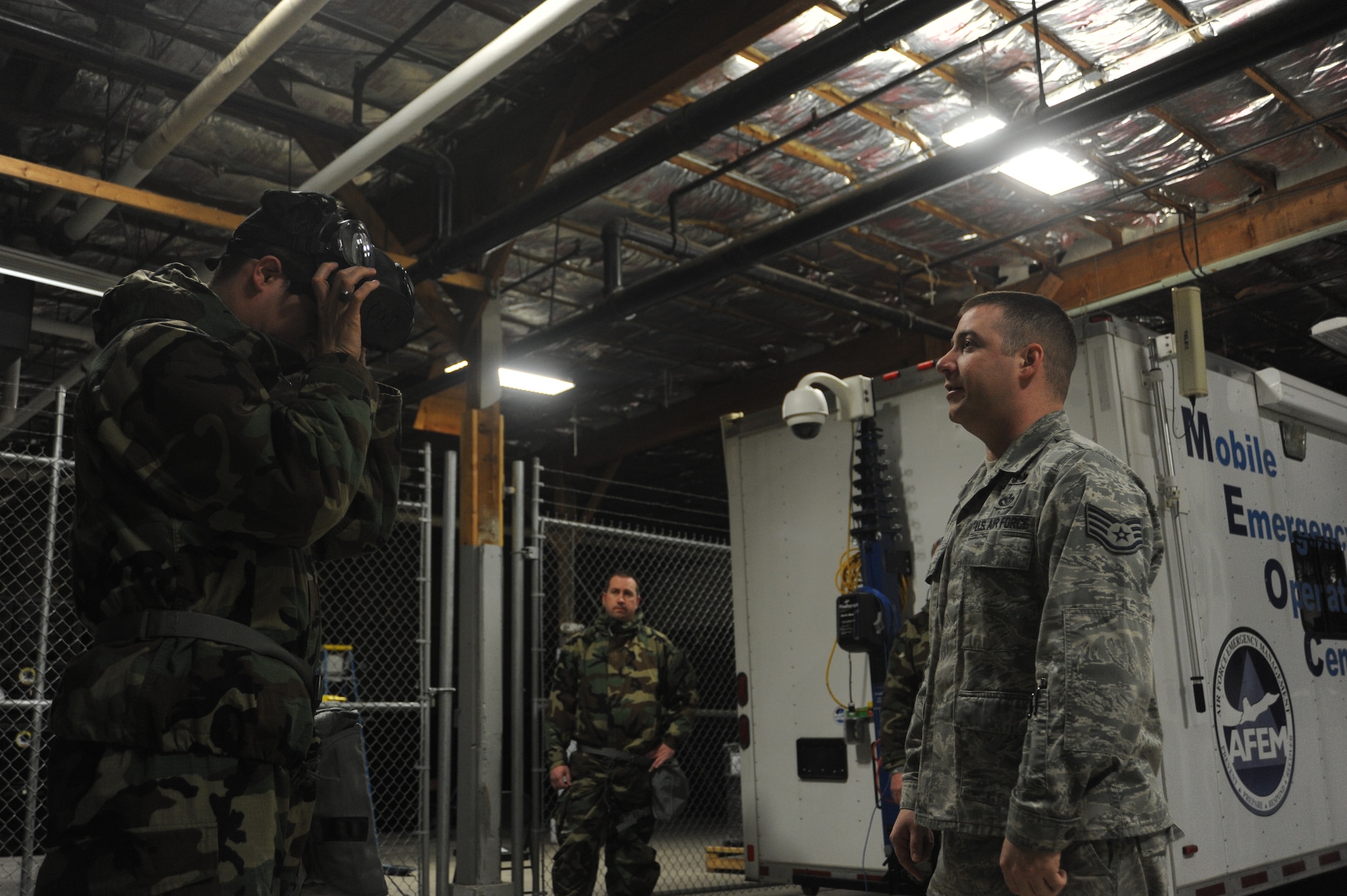 Staff Sgt. Jeremy Parks advises an Airman on proper gas mask wearing procedure at Fairchild Air Force Base, Wash., April 10, 2014.  The demonstration is part of the weekly Chemical, Biological, Radiological and Nuclear training held at the base.  Parks is the 92nd Chemical Engineer Squadron emergency management logistics NCO in charge.  (U.S. Air Force photo by Airman 1st Class Sam Fogleman/Released)