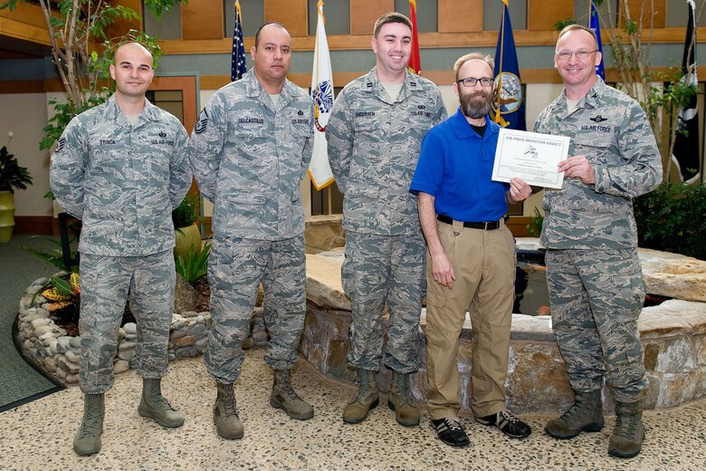 Col. Scott Graham (right), Air Force Inspection Agency, presents the Mortuary Affairs Entitlements Branch with a team award April 11, 2014, at Dover Air Force Base, Del. The award was presented at the conclusion of Air Force Mortuary Affairs Operation's Unit Effectiveness Inspection. Team awards were also presented to the Command, Control and Communication team and the Plans and Programs team. AFMAO received a Highly Effective rating from AFIA. (U.S. Air Force photo/Roland Balik)
