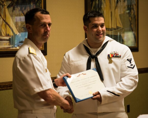Admiral John Richardson, Director of the Naval Nuclear Propulsion Program, presents Petty Officer 3rd Class Travis Kirckof the medal citation awarding Kirckof the Navy and Marine Corps Medal April 11, 2014, at Joint Base Charleston – Weapons Station. Kirckof received the medal for his heroic actions while serving as a Search and Rescue Swimmer on USS Guardian (MCM 5), where he helped 46 of his shipmates to safety after the Guardian ran aground on a reef in the Sulu Sea, Jan. 17, 2013. (U.S. Air Force photo/Senior Airman Dennis Sloan) 