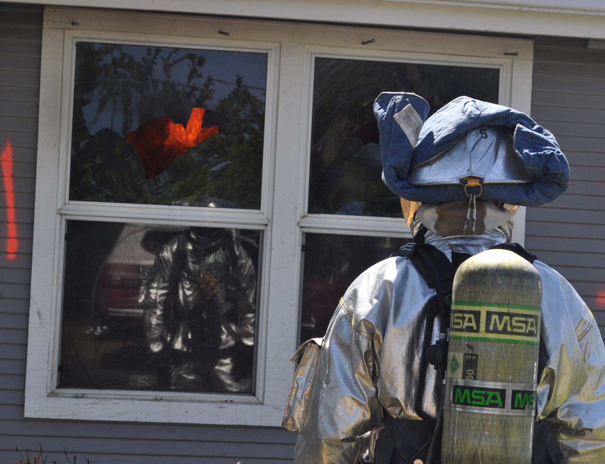 A firefighter from Travis Air Force Base watches as a fire inside a house catches and flames up. Burning inside the house was part of the live fire training held April 5 and 6 between Travis, Beale Air Force Base and local civilian fire departments. (U.S. Air Force photo/Ellen Hatfield)