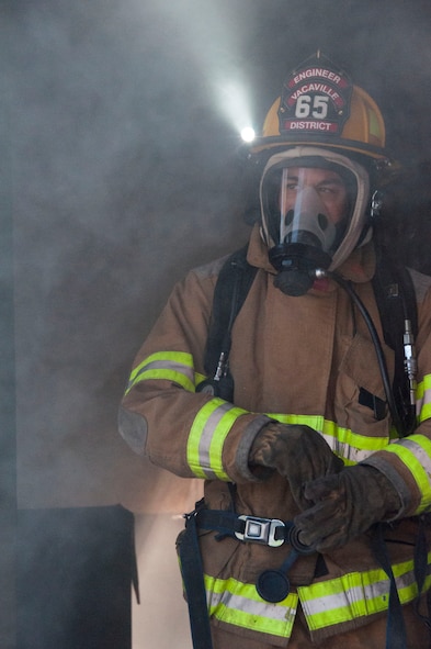 A firefighter exits a house filled with pallets topped with burning straw and paper. (U.S. Air Force photo/Staff Sgt. Cindy Alejandrez)