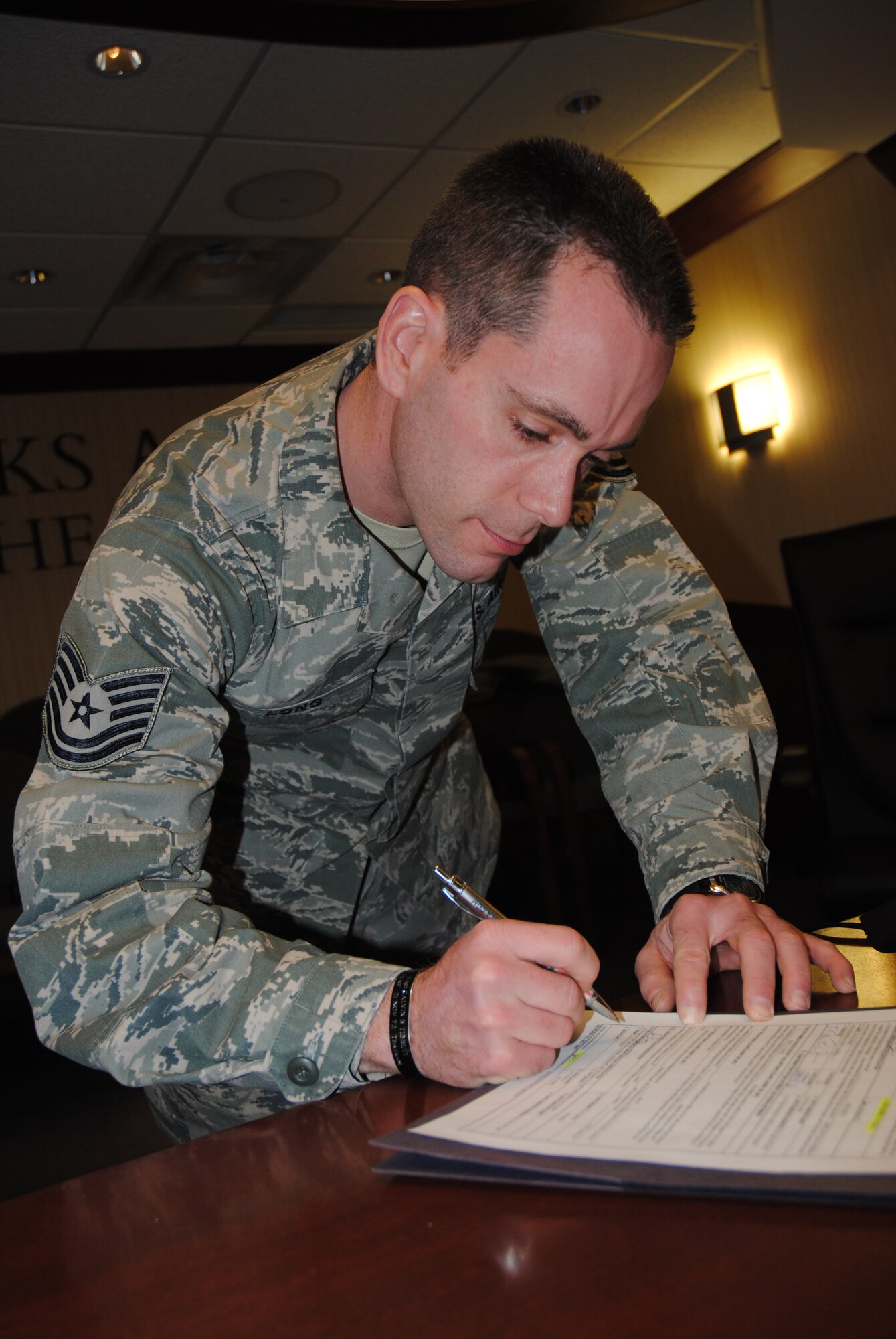 Tech. Sgt. Rick Long Jr., 69th Maintenance Squadron flightline expediter, signs his reenlistment contract after taking the  oath of enlistment from his father, retired Air Force Capt. Rick Long Sr., on April 2, 2014, during a re-enlistment ceremony digitally broadcast between Grand Forks Air Force Base, N.D. and Wright -Patterson Air Force Base, Ohio. Sergeant Long reenlisted for five more years in the Air Force. (U.S. Air Force photo/Staff Sgt. Luis Loza Gutierrez)
