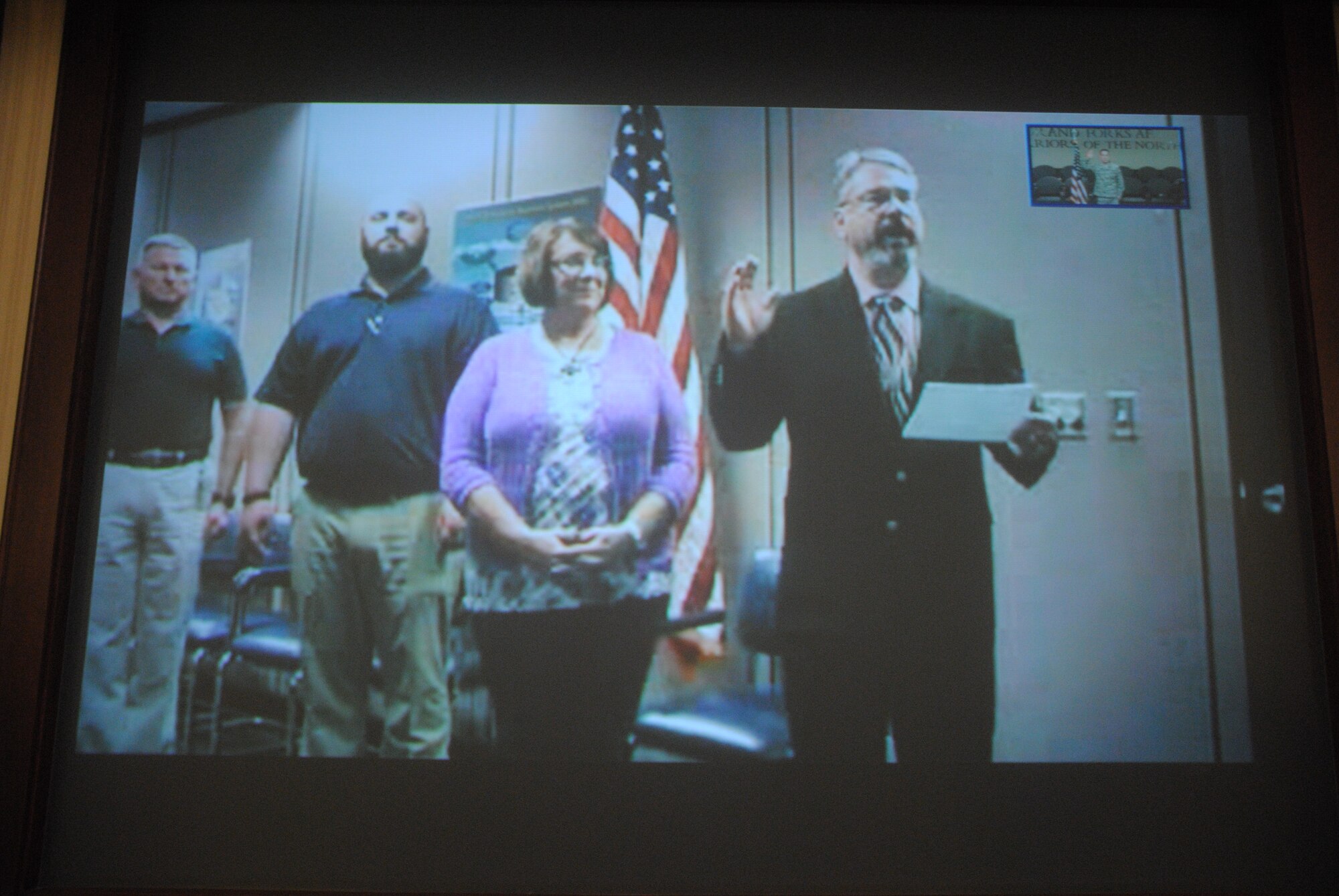 Retired Air Force Capt. Rick Long Sr. administers the Oath of Enlistment to his son, Tech. Sgt. Rick Long Jr., on April 2, 2014, during a reenlistment ceremony digitally broadcast between Grand Forks Air Force Base, N.D. and Wright -Patterson Air Force Base, Ohio. Sergeant Long’s younger brother, Ryan, and mother Ruth were also present during the ceremony. (U.S. Air Force photo/Staff Sgt. Luis Loza Gutierrez)