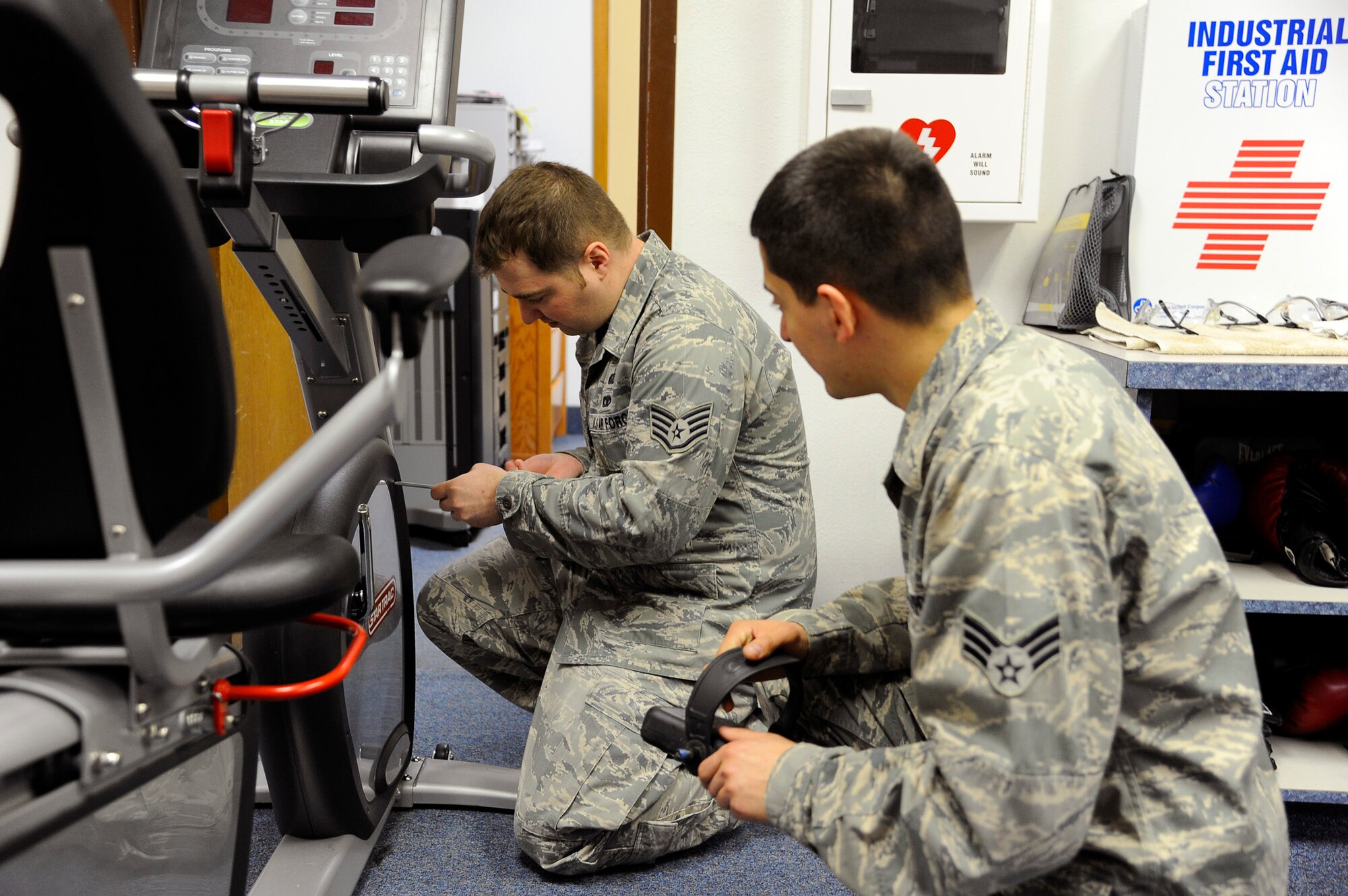 Senior Airman Justin Ruiz, 341st Force Support Squadron fitness specialist (right), assists Staff Sgt. Phillip Owens, 341st FSS fitness specialist, with repairing a stationary bike April 7 at Malmstrom’s Fitness Center. Throughout the day, fitness center personnel perform routine maintenance and repair on all the facilities equipment while keeping moveable pieces of gear organized and accounted for. (U.S. Air Force photo/Airman 1st Class Collin Schmidt)