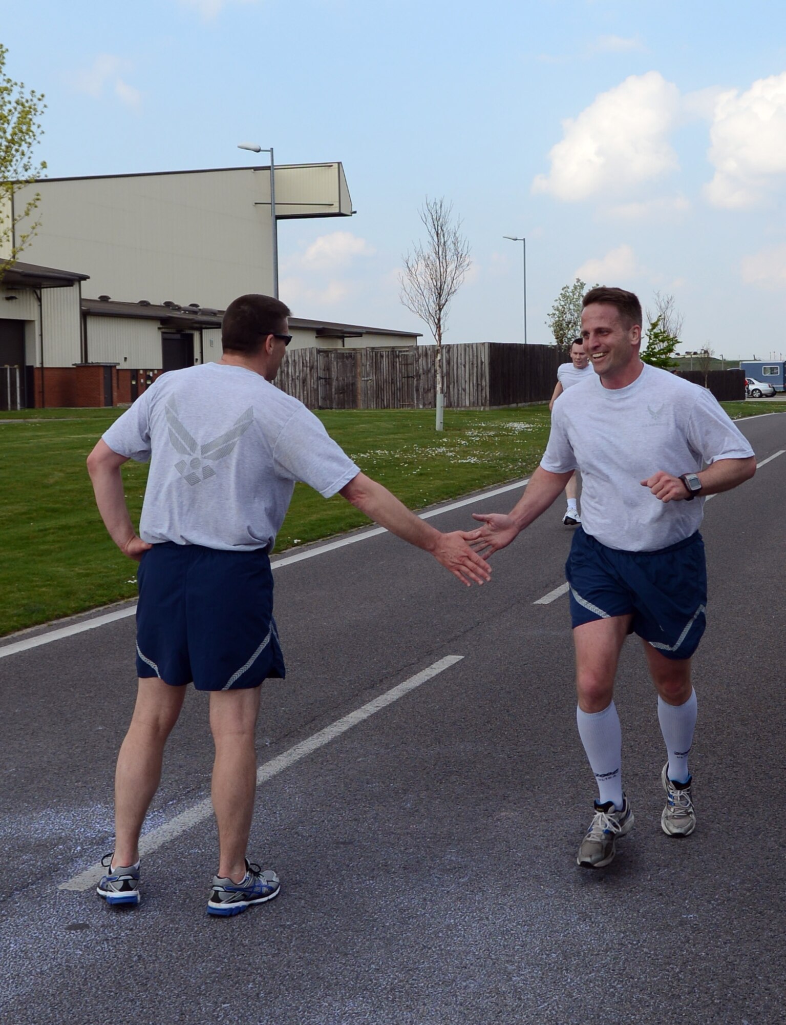 U.S. Air Force Chief Master Sergeant Tracy Jones, left, 100th Air Refueling Wing command chief, high-fives U.S. Air Force Col. David Cox, 100th ARW vice commander, as he finishes the wing run April 11, 2014, on RAF Mildenhall, England. The monthly 5 km run encourages morale and camaraderie through exercise and healthy competition. Service members, civilians and their families participated in the 5 km run. (U.S. Air Force photo by Airman 1st Class Jonathan Light/Released)
