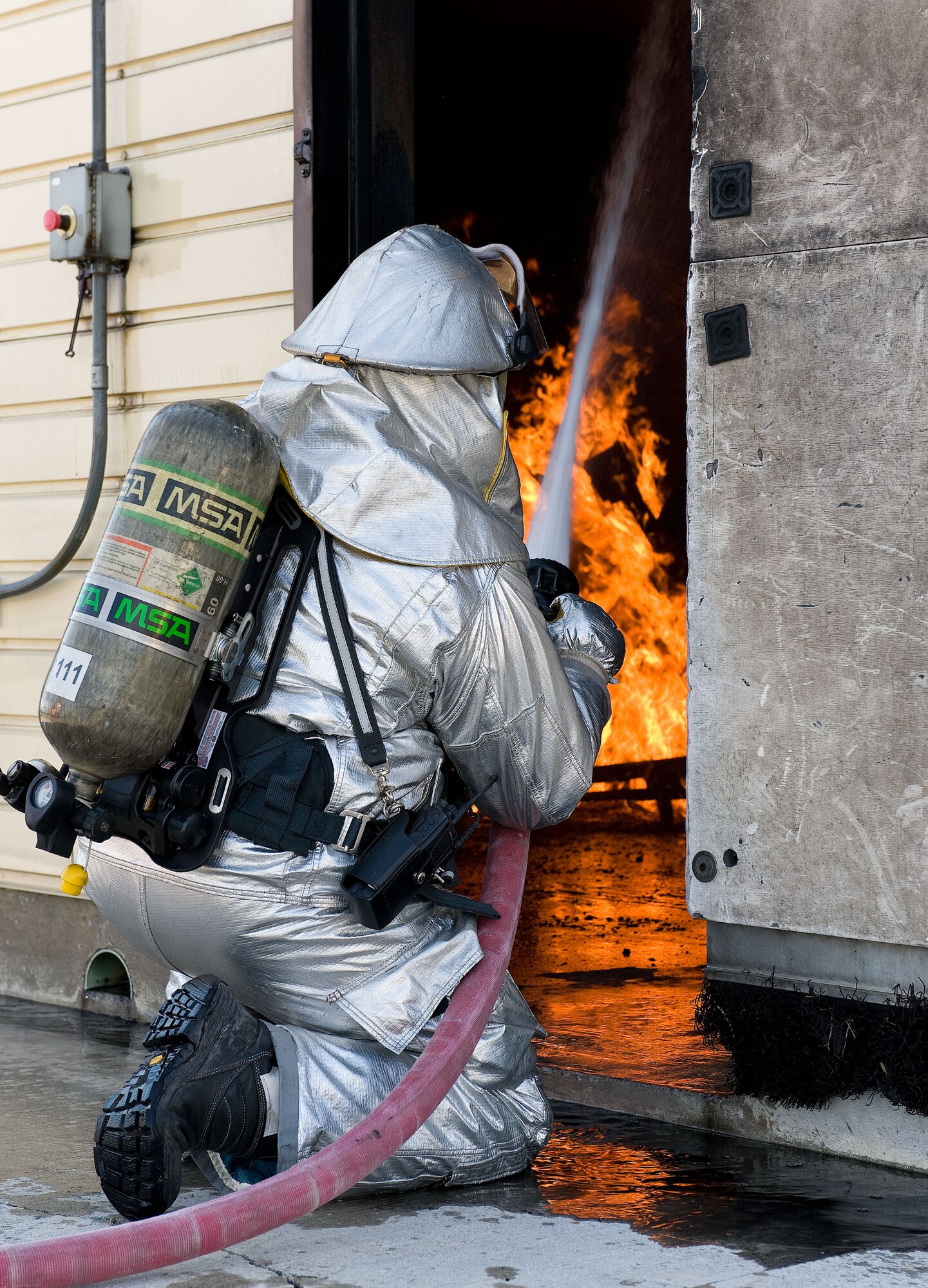 A firefighter from the 436th Civil Engineer Squadron Fire Department extinguishes flames during a simulated structural fire April 9, 2014, at the fire department training area on Dover Air Force Base, Del. Firefighters practiced extinguishing fires in the structural live fire trainer. (U.S. Air Force photo/Roland Balik)