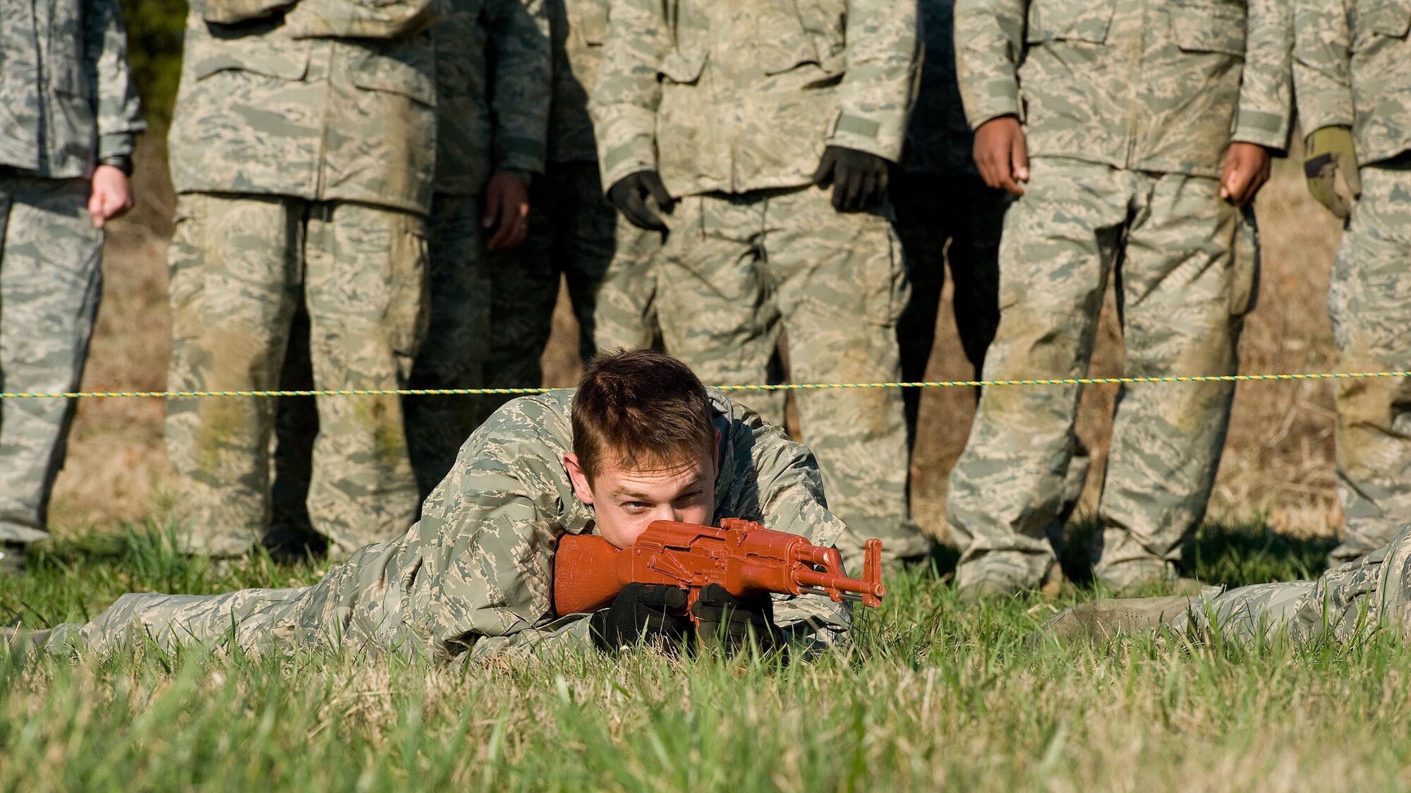 Staff Sgt. Alex Bechtler, a 436th Civil Engineer Squadron structural craftsman, lays in the prone position after crawling under simulated concertina wire April 9, 2014, at the deployment training area on Dover Air Force Base, Del. Personnel crawled under simulated concertina wire on their backs while holding a mock M16 rifle and then went into the prone firing position. (U.S. Air Force photo/Roland Balik)