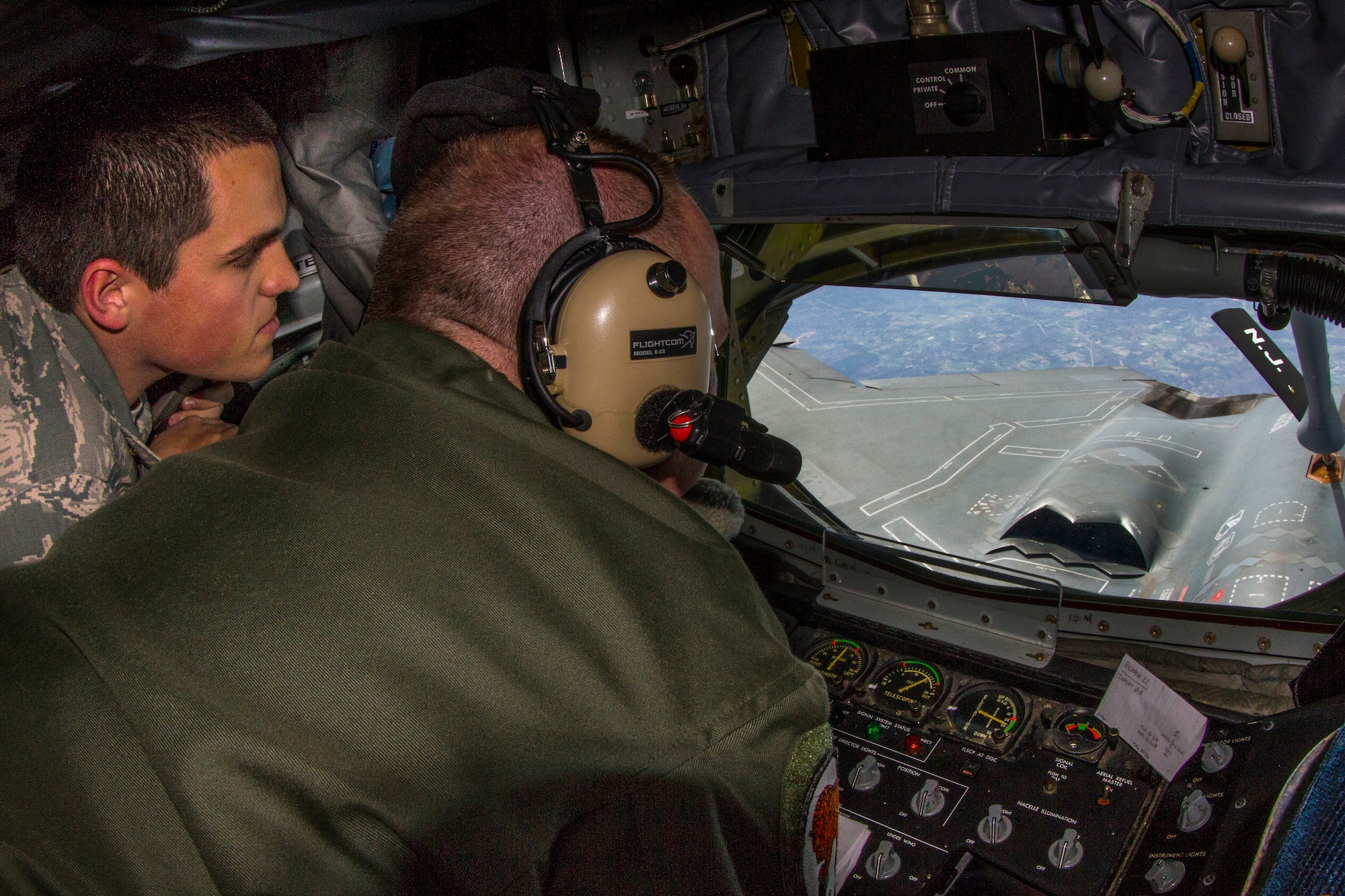 Chief Master Sgt. Brian S. Kilpatrick, front, boom operator, prepares to refuel a B-2 Stealth bomber assigned to the 509th Bomb Wing, as cadet Nick Strittmatter, left, observes the mission April 2, 2014. (U.S. Air National Guard photo by Master Sgt. Mark C. Olsen/Released)