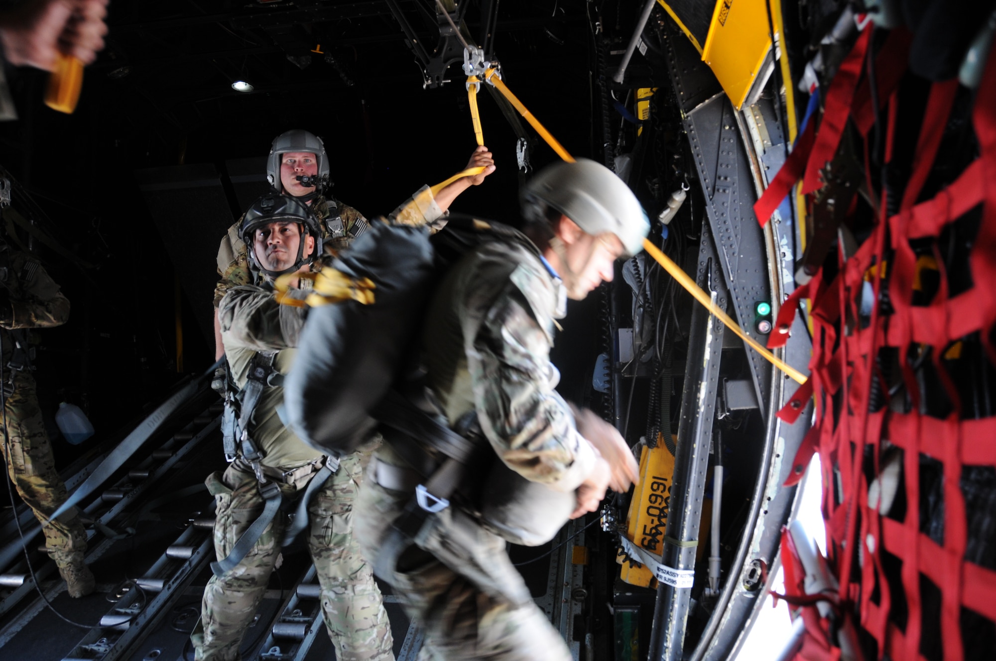 A 7th Special Forces Group jumpmaster directs paratroopers as they depart from a C-130 Hercules aircraft during a joint airborne operations training jump with the Honduran military at Soto Cano Air Base, Honduras on April 3, 2014.  .  The 1,500 foot static line jump allowed members from both nations to retain currency, while also strengthening the relationship between the U.S. and Honduran forces.  (Photo by U. S. Air National Guard Capt. Steven Stubbs)