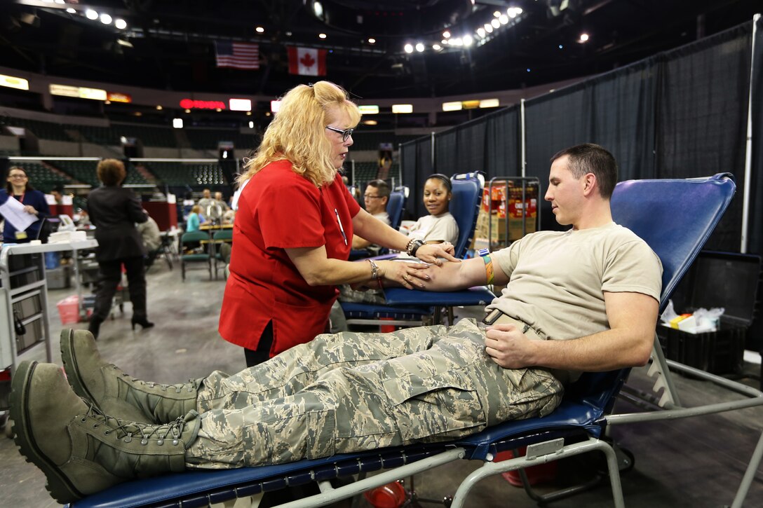 U.S. Air Force Staff Sgt. David Savino, right, watches as a nurse identifies a vein from where blood will be drawn. The 108th Wing finance management journeyman was part of the approximate 200 Soldiers and Airmen from the New Jersey National Guard who volunteered to donate blood at the Super Community Blood Drive at the Sun National Bank Center in Trenton, N.J., Jan. 14, 2014. (NJDMAVA photo by Tech. Sgt. Armando Vasquez/Released) 