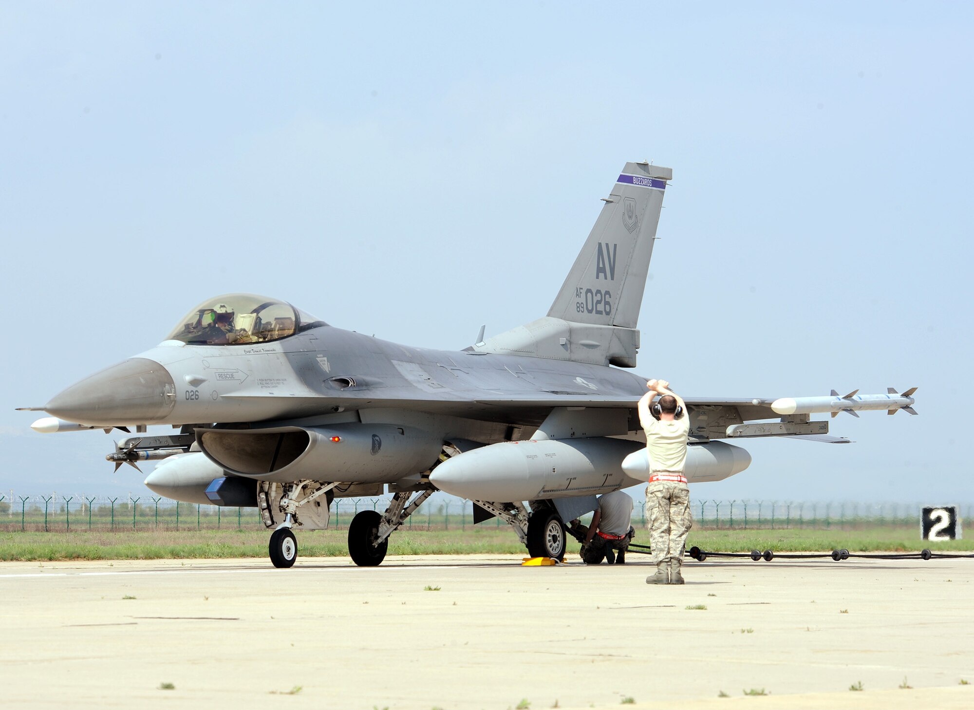Senior Airman Adrian Connors, 31st Maintenance Squadron crash recovery technician, signals an F-16 Fighting Falcon pilot April 9, 2014, at Campia Turzii, Romania, during an arresting cable system test. The system catches an aircraft’s tail hook when its brake system is inoperable. (U.S. Air Force photo/Staff Sgt. R.J. Biermann)