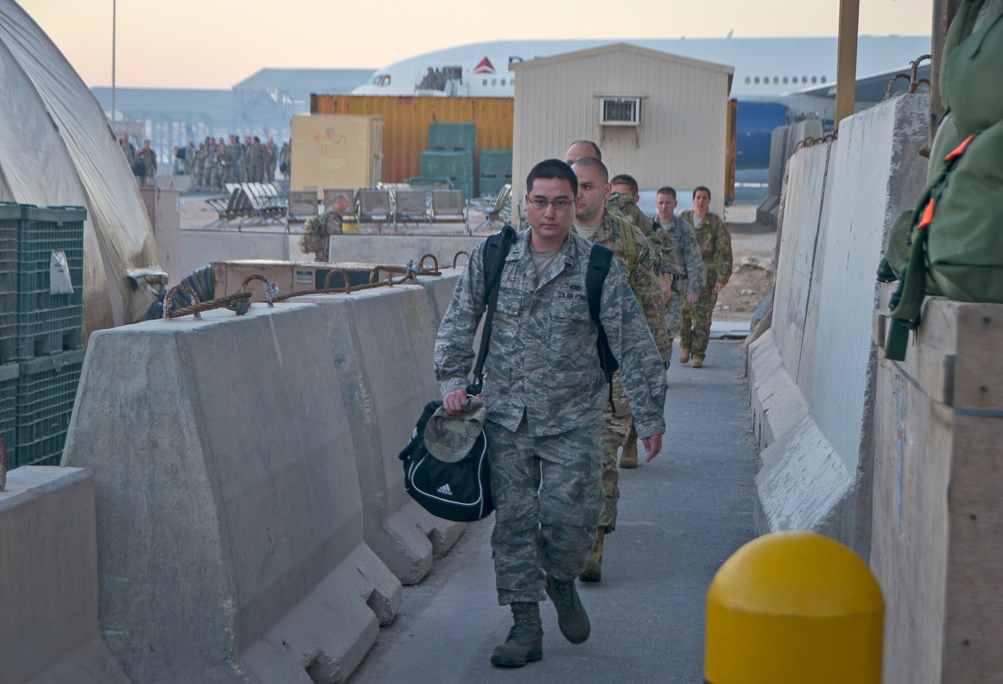 Airmen walk with their carry-on bagage after ariving at Al Udeid Air Base, Qatar, April 8, 2014. Every year more than 150,000 military personnel travel through AUAB and the coordination of getting those service members to their final destination is done by the Air Force Transient Reception Control Center. (U.S. Air Force photo/ Senior Airman Jared Trimarchi)