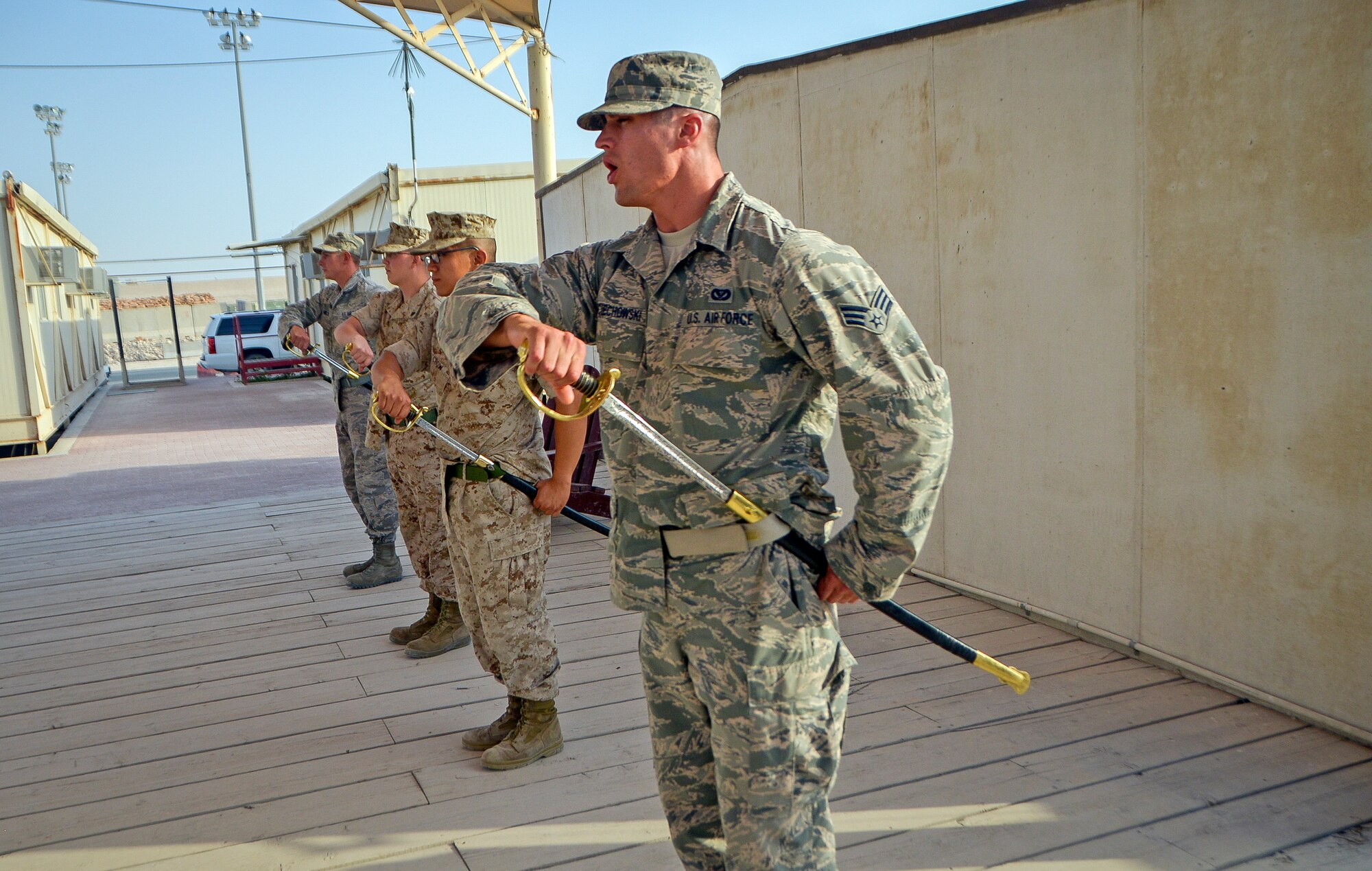 Airmen and Marines practice sword procedures during a Marine Tactical Electronic Warfare Squadron 3 Corporals Course at Al Udeid Air Base, Qatar, April 9, 2014. The course, which is similar to Airman Leadership School, is 2 and a half weeks long and encompasses professional ethics, combat operations, public speaking, sword and guidon procedures, social media guidance and physical training. Five Airmen along with 12 Marines are currently participating in the course. (U.S. Air Force photo/ Senior Airman Jared Trimarchi) 
