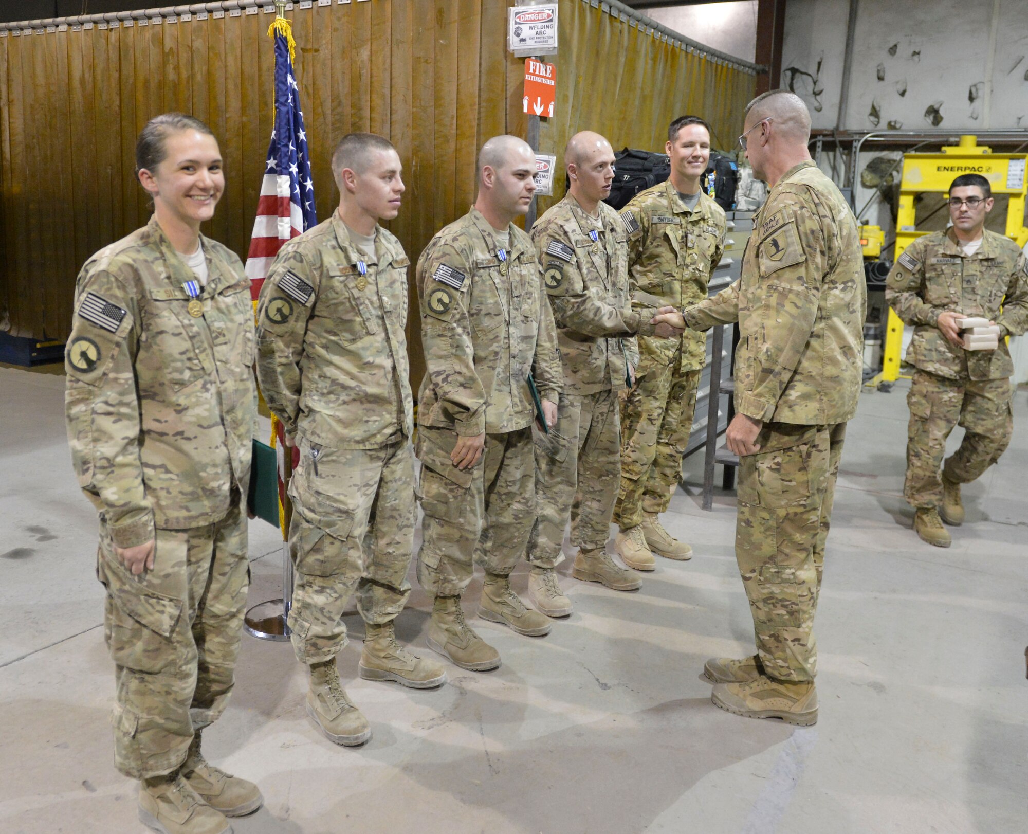 Airmen from the 455th Metal Fabrication shop shake hands with Army Command Sgt. Major Lambeth after being presented the Army Achievement medal at Bagram Airfield, Afghanistan, April 9, 2014. The Airmen were recognized for quickly manufacturing parts needed to get Army helicopters repaired and returned to flying status..(U.S. Air Force photo by Senior Master Sgt. Gary J. Rihn/Released)