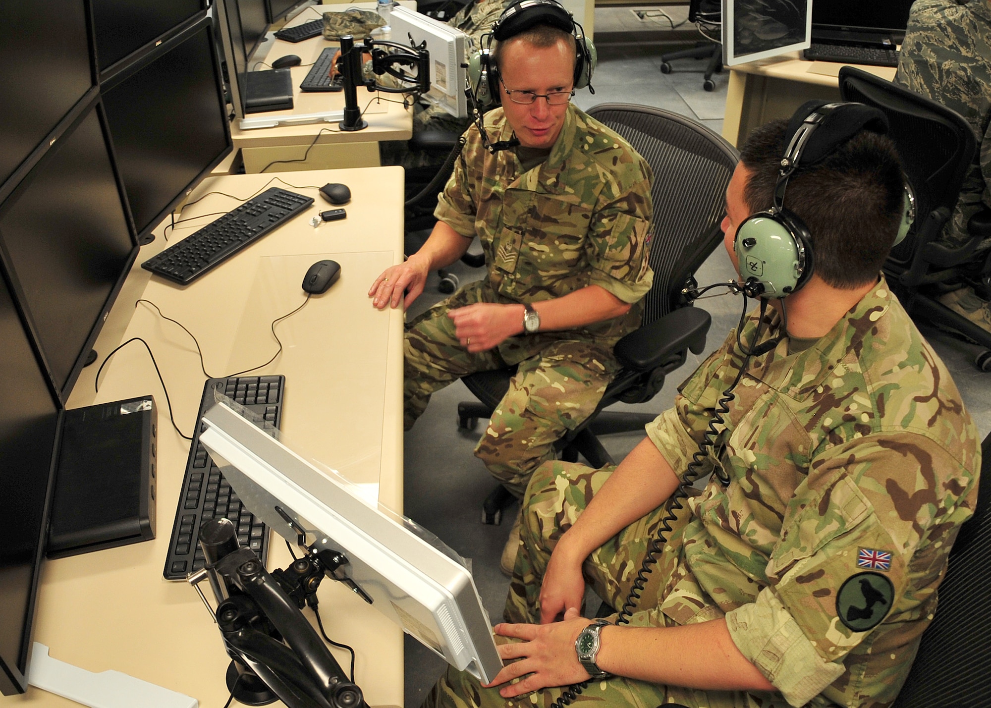 U.K. Royal Air Force Flt. Sgt. Daz Hucknall and Fg. Off. Andrew North, both assigned to the 727th Expeditionary Air Control Squadron, become familiar with the weapons director position on the Battlespace Command and Control Center Theater operations floor at an undiscloded location in Southwest Asia, April 9, 2014. Hucknall and North are both from Nottingham U.K. (U.S. Air Force photo by Staff Sgt. Michael Means/Released)