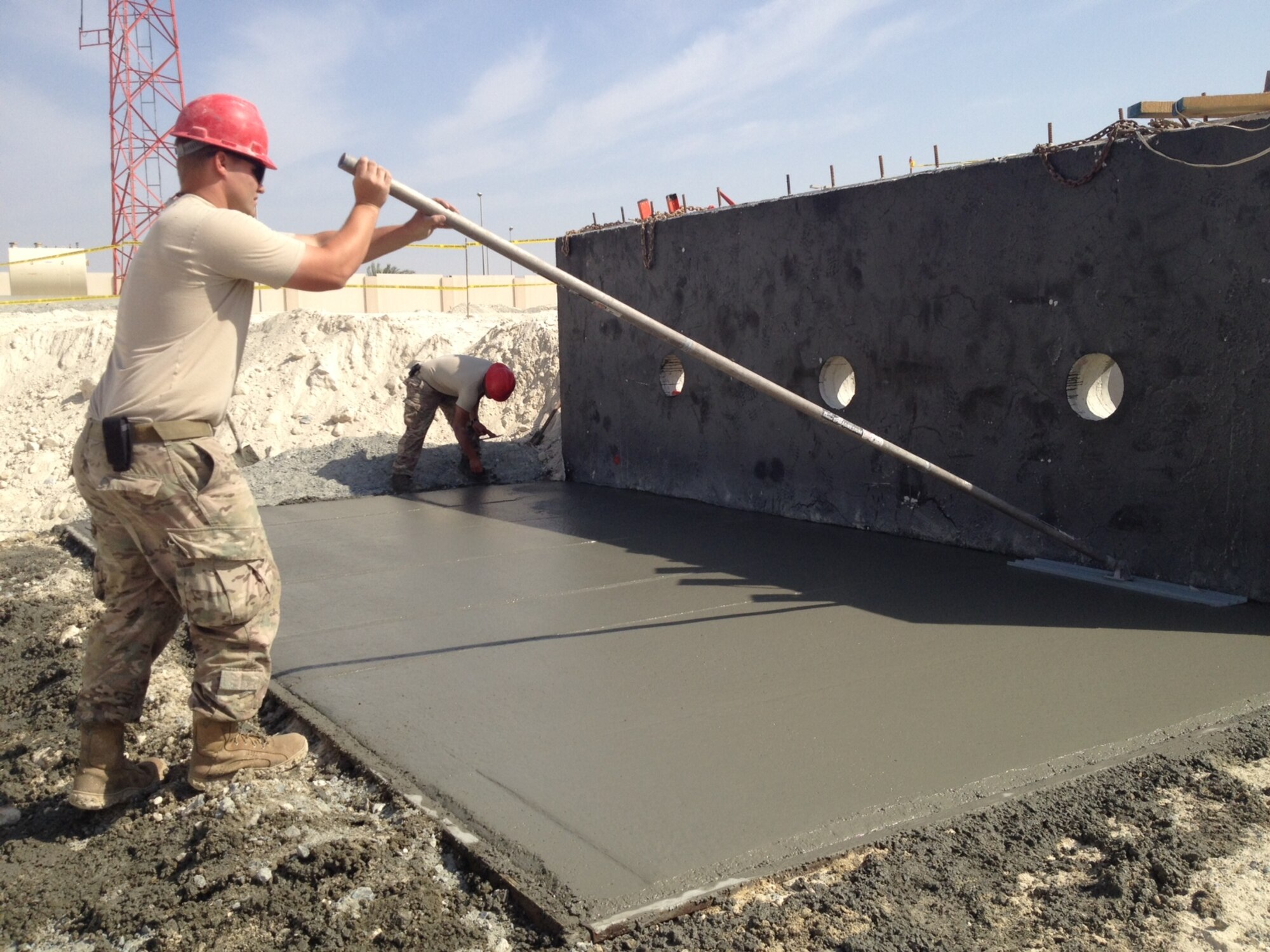 Senior Airman Brendon Luke, 380th Expeditionary Civil Engineer Squadron, floats concrete to serve as a binding pad for a new sewage lift station at an undisclosed location in Southwest Asia. (Courtesy photo by Capt. Amy Peabody)