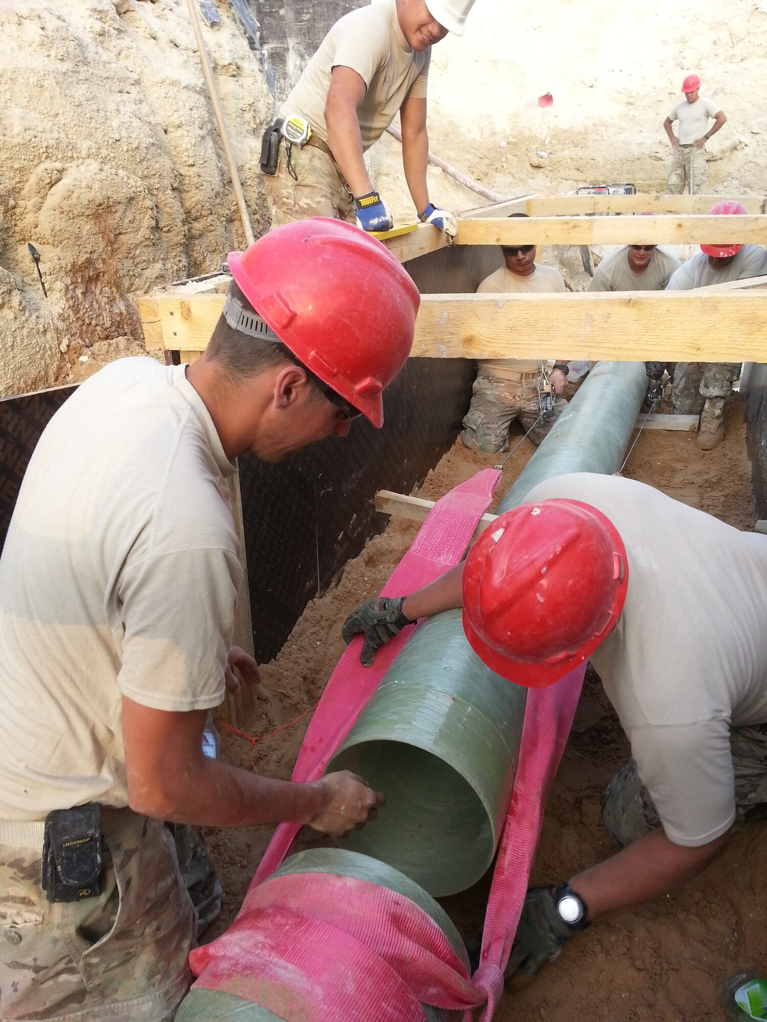 Staff Sgt. Michael Shortsleeve, 557th Expeditionary Prime Base Engineer Emergency Force Squadron, and Staff Sgt. Ivan Alandzak, 380th Expeditionary Civil Engineer Squadron, install a 20 foot section of glass reinforces pipe for a new sewage lift station at an undisclosed location in Southwest Asia. (Courtesy photo by Capt. Amy Peabody)