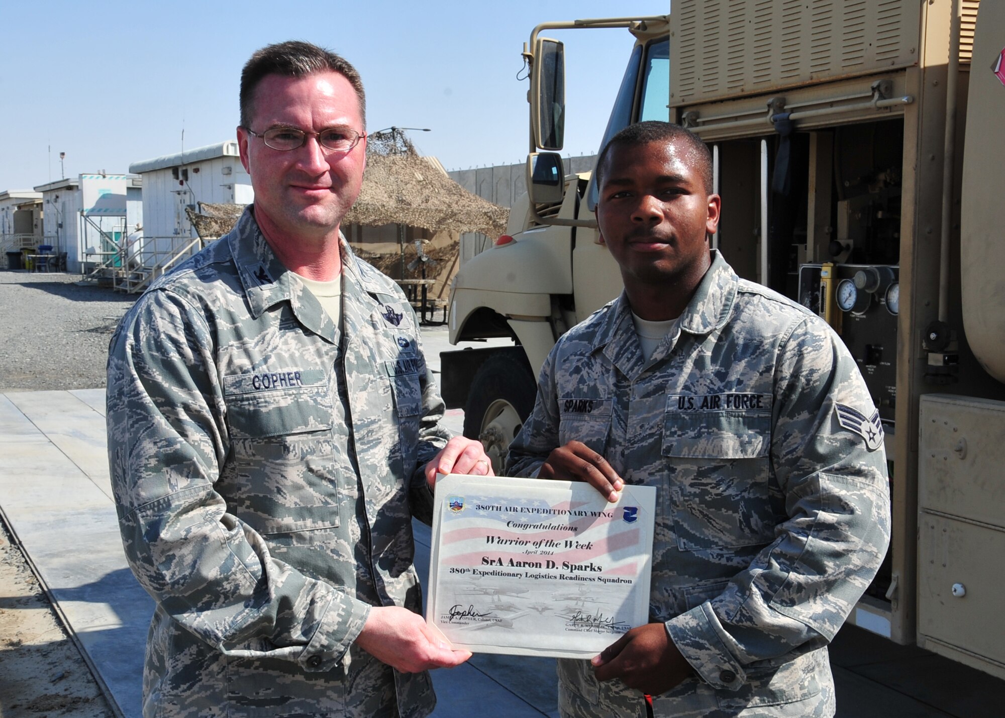 Air Force Col. James Copher, 380th Air Expeditionary Wing vice commander, presents Air Force Senior Airman Aaron Sparks, 380th Expeditionary Logistics Readiness Squadron fuels distribution operator, a warrior of the week certificate at an undisclosed location in Southwest Asia, April 9, 2014. Sparks is a native of Mobile Ala., and is deployed from McConnell Air Force Base, Kan. (U.S. Air Force photo by Staff Sgt. Michael Means/Released)