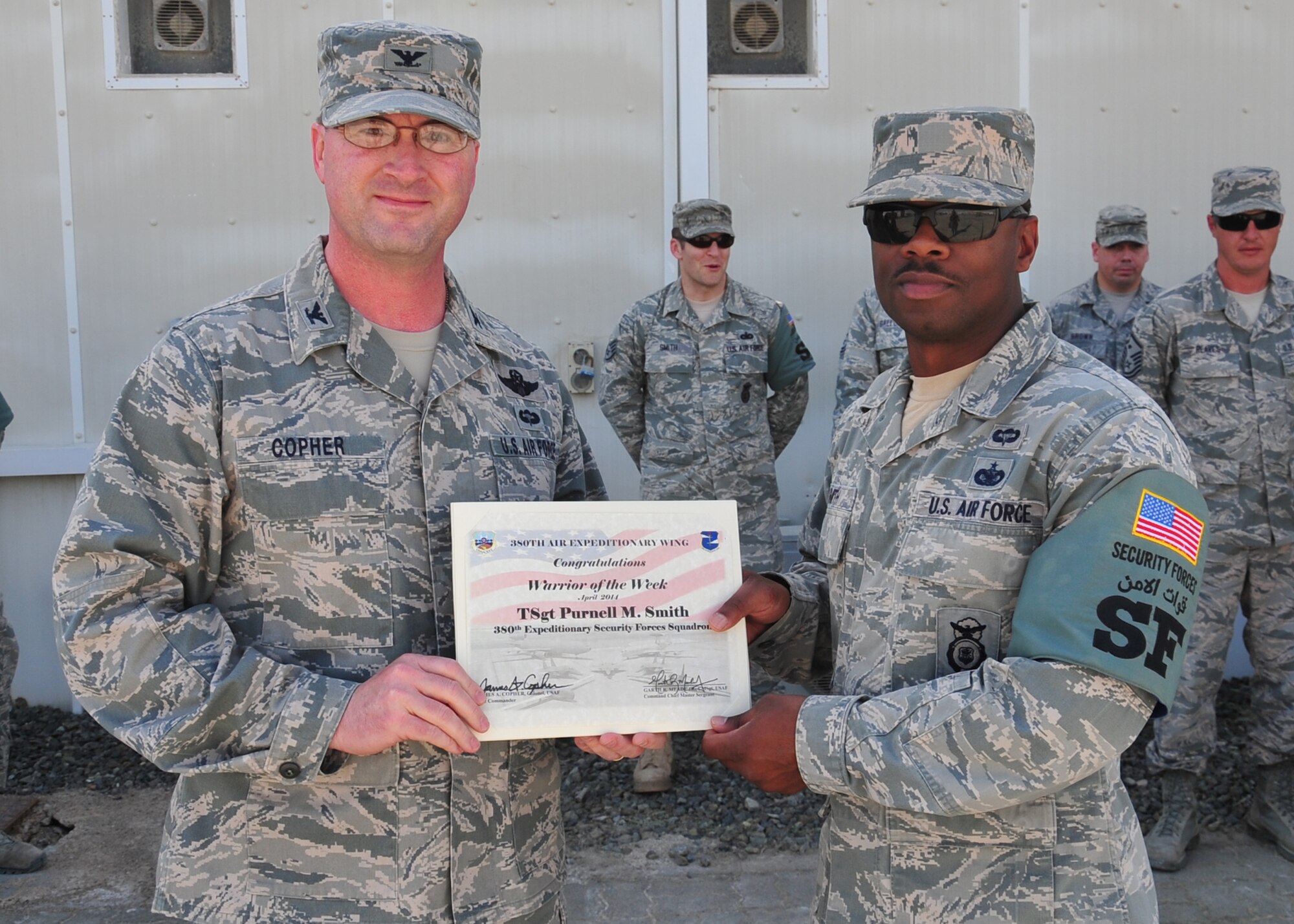 Air Force Col. James Copher, 380th Air Expeditionary Wing vice commander, presents Air Force Tech Sgt. Purnell Smith, 380th Expeditionary Security Forces Squadron unit deployment manager, a warrior of the week certificate at an undisclosed location in Southwest Asia, April 9, 2014. Smith is a native of Decatur Ga., and is deployed from Ellsworth Air Force Base, S.D. (U.S. Air Force photo by Staff Sgt. Michael Means/Released)
