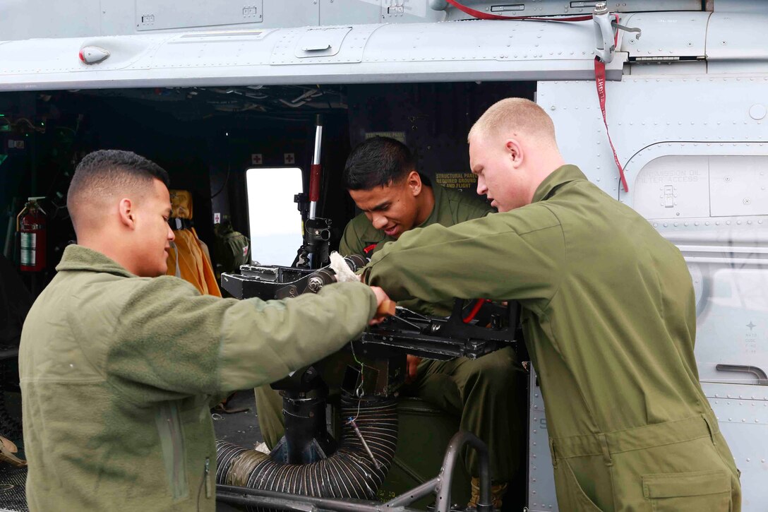 Lance Cpls Christopher Davis, Joshua Tanoa and Rizo Oscar, flightliners with Marine Medium Tiltrotor Squadron 163 (Reinforced), 11th Marine Expeditionary Unit, clean the weapons system of a UH-1Y Huey during Amphibious Squadron Marine Expeditionary Unit Integration Training (PMINT), off the coast of San Diego, April 10, 2014. PMINT is the first at-sea event in the 11th MEUs predeployment training program where the unit will conduct live training operations alongside the Makin Island Amphibious Ready Group. (U.S. Marine Corps photo by Gunnery Sgt. Jimmy H. Bention, Jr/Released)