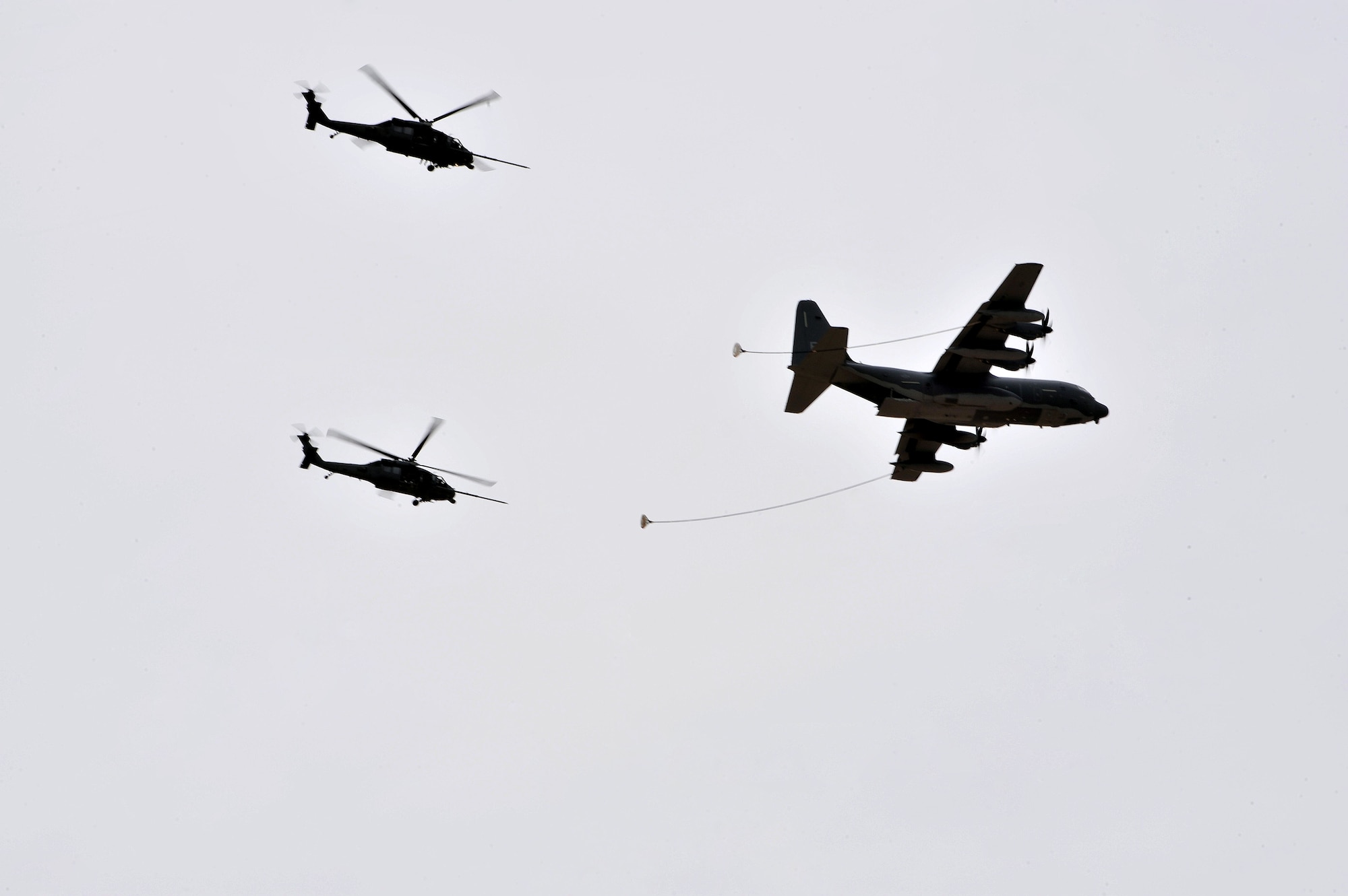 Two HH-60 Pavehawks fly behind an HC-130J Combat King during the Open House at Davis-Monthan Air Force Base, Ariz., April 12, 2014.The HH-60’s and HC-130J were demonstrating their refueling methods for the thousands of people in attendance. (U.S. Air Force Photo by Senior Airman Josh Slavin/Released)