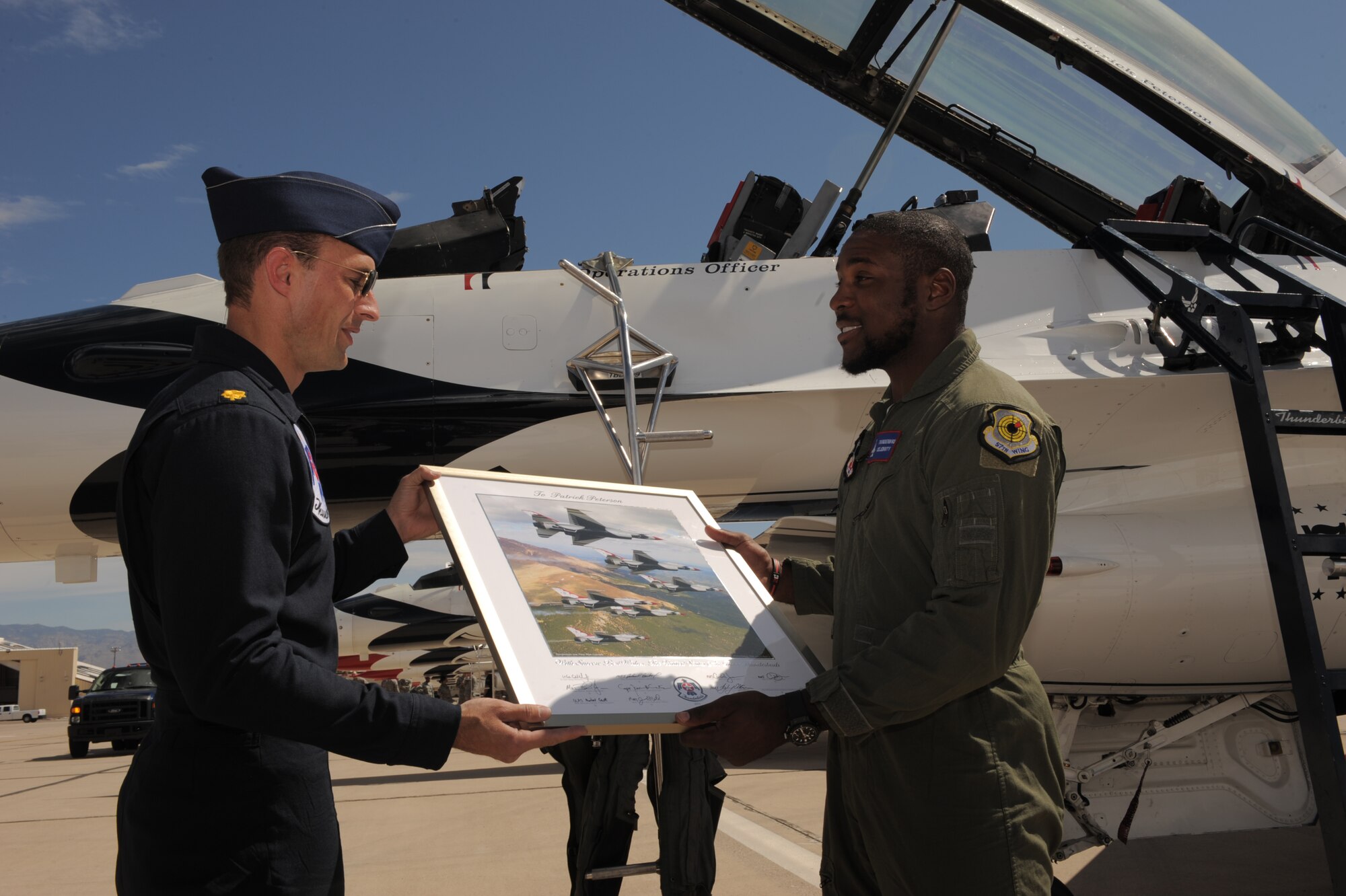 U.S. Air Force Maj. Tyler "Wolf" Ellison, USAF Thunderbirds Air Demonstration Squadron operations officer, presents Patrick Peterson, Arizona Cardinals cornerback, with a keepsake at Davis-Monthan Air Force Base, Ariz., April 11, 2014. The keepsake was signed by each pilot apart of the Thunderbirds team. (U.S. Air Force photo by Airman 1st Class Chris Drzazgowski/Released)