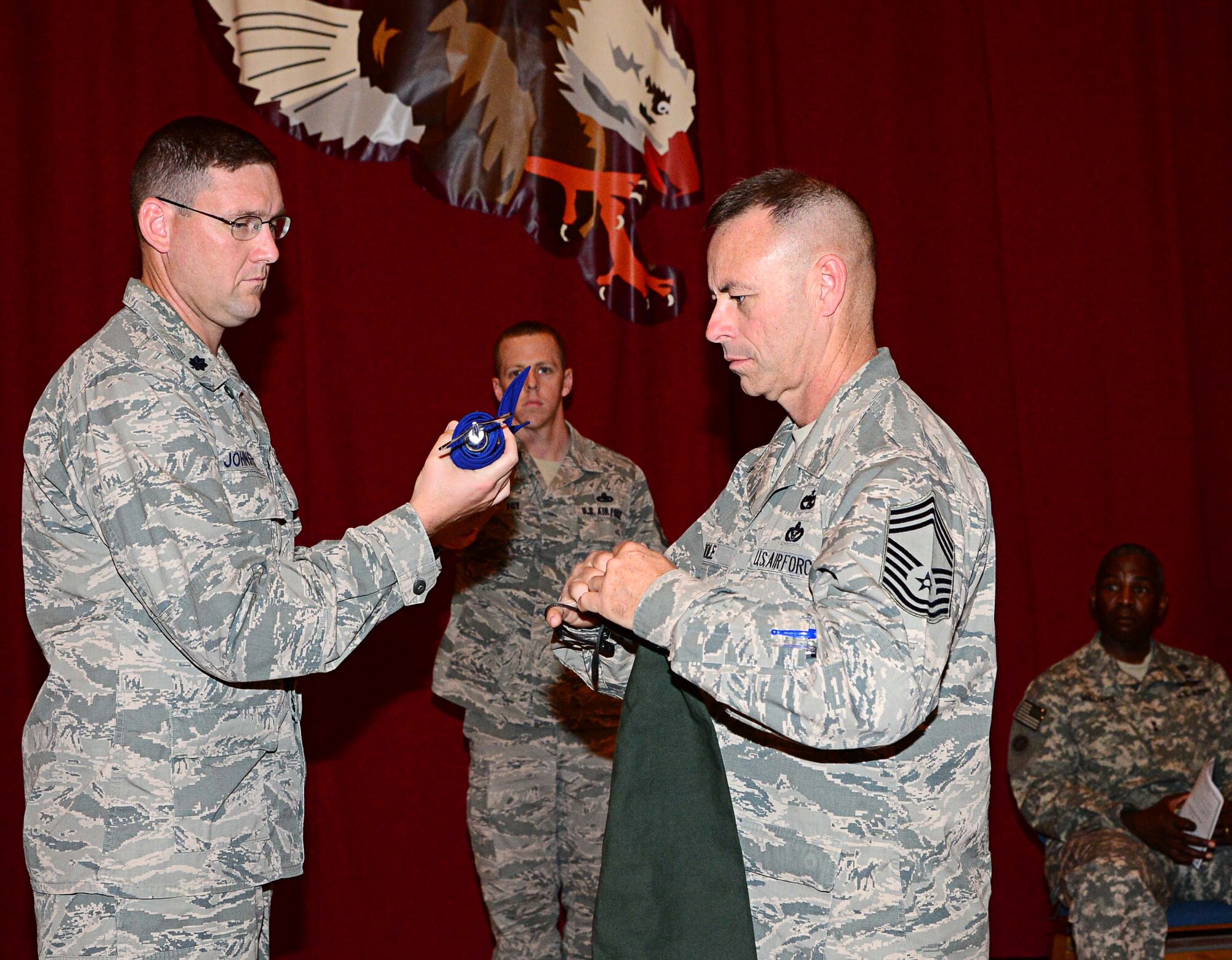 Lt. Col. Dan Johnstone, Commander of the 387th Air Expeditionary Squadron and Chief Master Sgt. George Role, 387th AES Chief Enlisted Manager, sheath's the unit's flag to signify the inactivation at an undisclosed location in Southwest Asia.
The 387th AES, has held the mission, which includes inspecting Department of
Defense personnel, vehicles and materials departing the CENTCOM area of
responsibility destined for the United States, during a seven month
rotation. The mission will now be handed over to the Marines of the 2nd Law
Enforcement Battalion, assigned to Camp Lejeune, N.C., who have been
training with the 387th Airmen on U.S. Customs and Border Clearance
procedures here. (U.S. Air Force photo by Senior Airman Desiree W. Moye)
