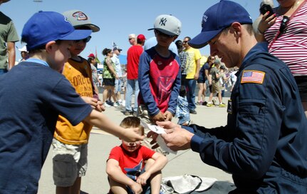 U.S, Air Force Major Rob Nichols, Wings of Blue demonstration team jump commander, receives a drawing from a child at the Thunder and Lightning over Arizona event at Davis-Monthan Air Force Base, Ariz., April 13, 2014. Nichols requested the help of children to pack his parachute after completing a free fall aerial demonstration. (U.S. Air Force photo by Staff Sgt. Angela Ruiz/Released)