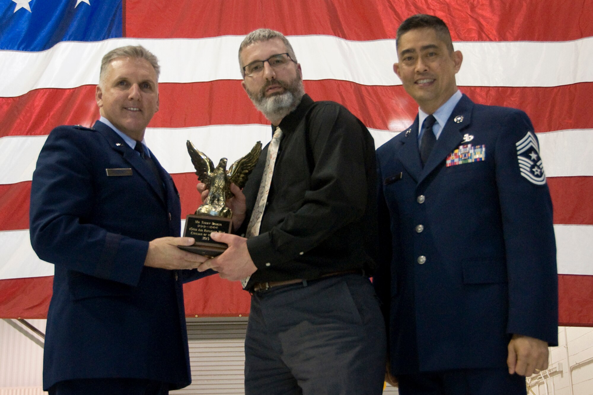 Brig. Gen. John C. Flournoy Jr., 4th Air Force commander, left, and Chief Master Sgt. Brian Wong, 4th AF command chief, right, present Terry Bodkin, 434th Security Forces Squadron police services manager, with a 434th Air Refueling Wing Civilian of the Year for 2013 award at an annual awards banquet held at Grissom Air Reserve Base, Ind., April 12, 2014. Each year, time is set aside to honor Grissom Airmen who embody the Air Force's core values to the fullest extent through their actions and commitment to duty. (U.S. Air Force photo/Staff Sgt. Andrew McLaughlin)
