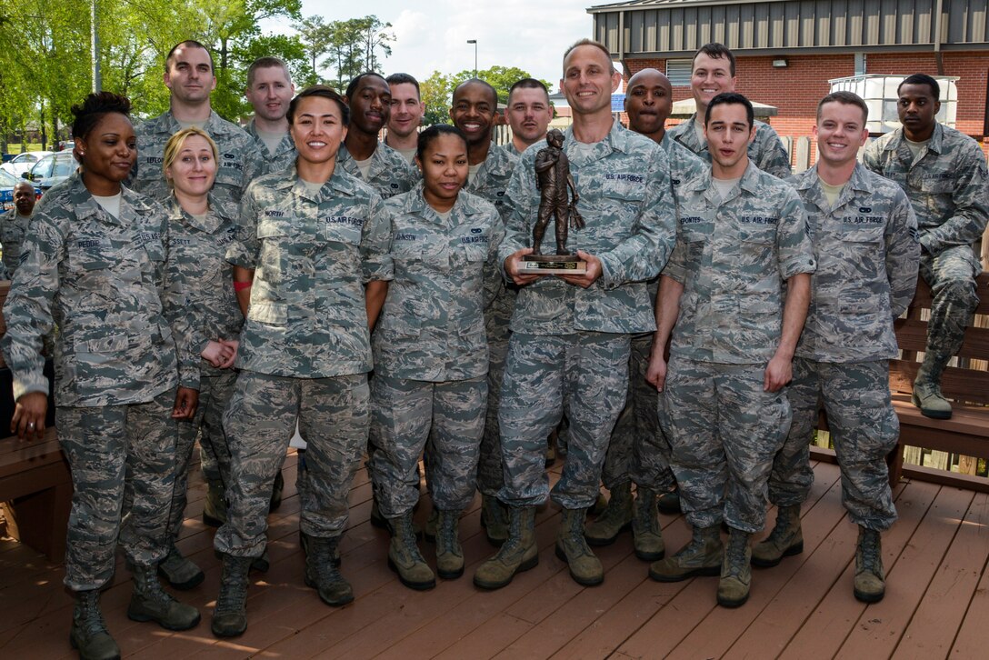 Airmen from both aerial port squadrons at Joint Base Charleston, S.C. proudly stand next to the Port Dawg Challenge trophy April 12, 2014. The event brought together the 38th and 81st Aerial Port Squadrons, both from the 315th Airlift Wing at Joint Base Charleston, who joined forces to compete in the challenge and showcase their aerial port skills. The day of events included pallet loading, load planning, a forklift obstacle course, simulated passenger processing and a joint inspection of a vehicle. (U.S. Air Force photo/Tech. Sgt. Shane Ellis) 