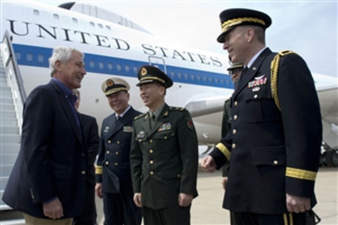 U.S. Defense Secretary Chuck Hagel, left, is greeted by U.S. Army Brig. Gen. Mark W. Gillette, right, U.S. defense attaché to China, and Chinese military officers in Qingdao, China, April 7, 2014. Hagel visited the Chinese aircraft carrier Liaoning while in Qingdao, the first foreigner to do so.