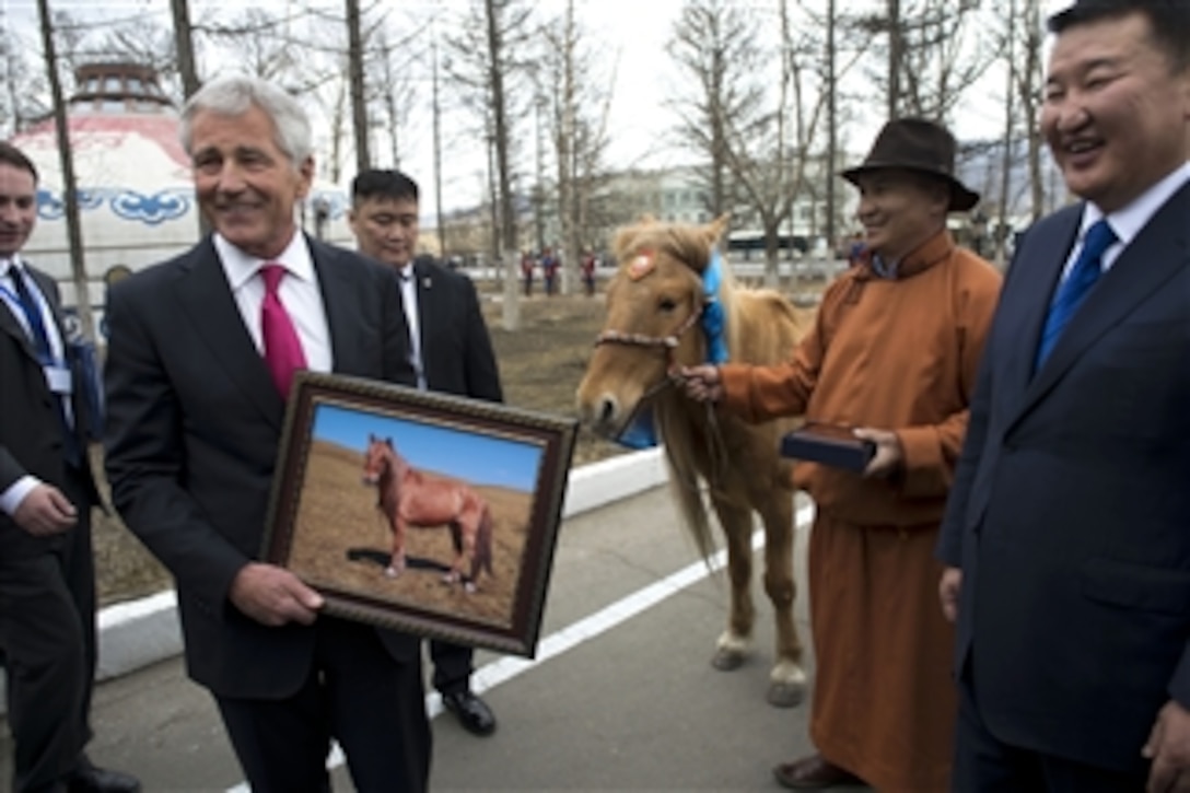 U.S. Defense Secretary Chuck Hagel holds a photograph of his horse as Mongolian Defense Minister Dashdemberal Bat-Erden looks on at the Mongolian Ministry of Defense in Ulaanbaatar, Mongolia, April 10, 2014. The horse is a traditional Mongolian gift to visiting dignitaries and is renamed during the gifting ceremony. Hagel renamed the horse Shamrock after his high school mascot.