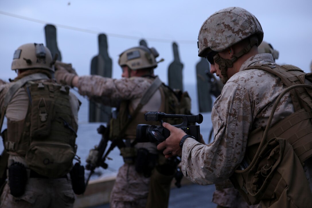 Lance Cpl. Evan R. White, a combat cameraman with the 11th Marine Expeditionary, films Marines of Maritime Raid Force as they conduct combat drills on the air cargo elevator of the USS Makin Island during Amphibious Squadron Marine Expeditionary Unit Integration Training (PMINT), off the coast of San Diego, Calif., April 10, 2014. PMINT is a two-week long pre-deployment training event focusing on the combined capabilities of the Marine Expeditionary Unit and Amphibious Ready Group (ARG), conducting amphibious operations, crisis response and limited contingency operations. (U.S. Marine Corps photo by Gunnery Sgt. Rome M. Lazarus/Released)