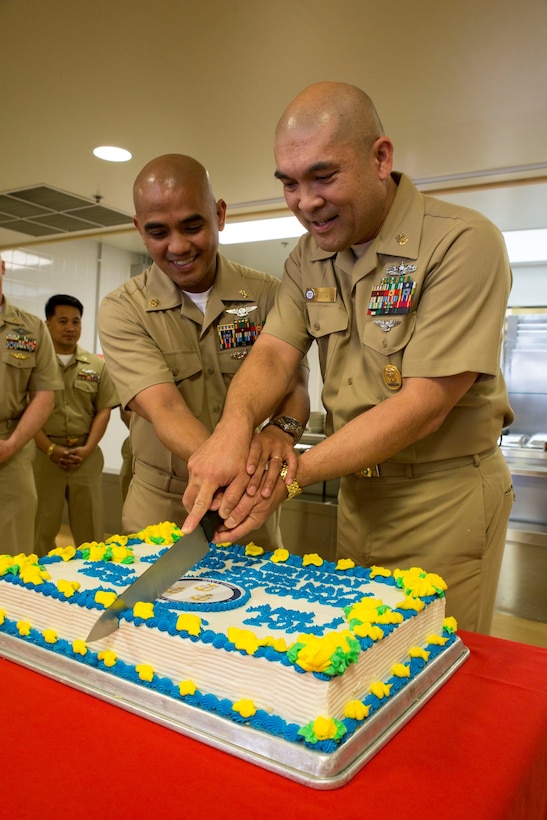 Master Chief Petty Officer Gilbert Ermitano, right, Navy senior enlisted advisor for Marine Corps Air Station Iwakuni, Japan, and Chief Petty Officer Jowel Kinney, production control chief for Marine Aviation Logistics Squadron 12, cut a cake during the Navy Chief 121st birthday celebration at the Southside Mess Hall aboard station April 1, 2014. 