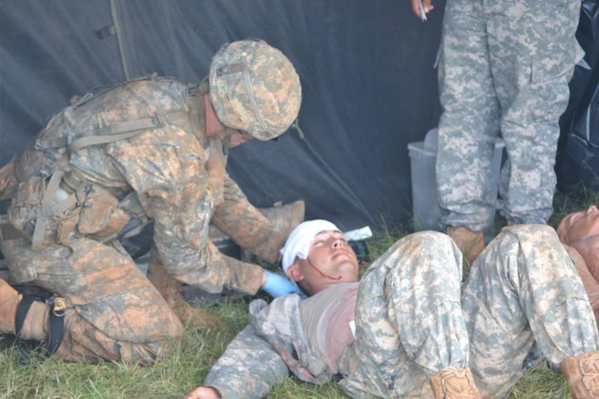 Expert Field Medical Badge course candidates apply a dressing to a simulated head injury during a mass casualty scenario in a casualty collection point set up at the EFMB course, which was held at Schofield Army Barracks, Hawaii, March 31 through April 11, 2014. To successfully complete the course, students must demonstrate their proficiency at tactical combat casualty care, standard and non-standard evacuation operations, take a written test, execute U.S. Army Warrior communications and chemical, biological, radiological, nuclear and high-yield explosives tasks, perform day and night land navigation and complete a 12-mile road march. (U.S. Army photo courtesy of 25th Infantry Division)