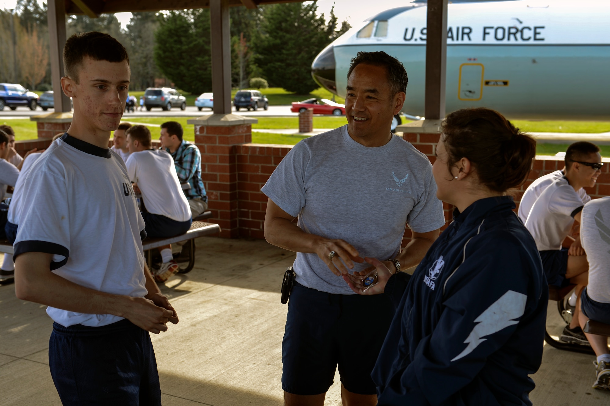 Col. David Kumashiro (middle), 62nd Airlift Wing commander, coins Cadets Lauren Brooks and Samuel Highnote, U.S. Air Force Academy students, at a burger burn after the Team McChord run, April 11, 2014 at Joint Base Lewis-McChord, Wash. Students were given the opportunity to socially visit with USAFA graduates assigned to McChord Field. (U.S. Air Force photo/Staff Sgt. Russ Jackson)
